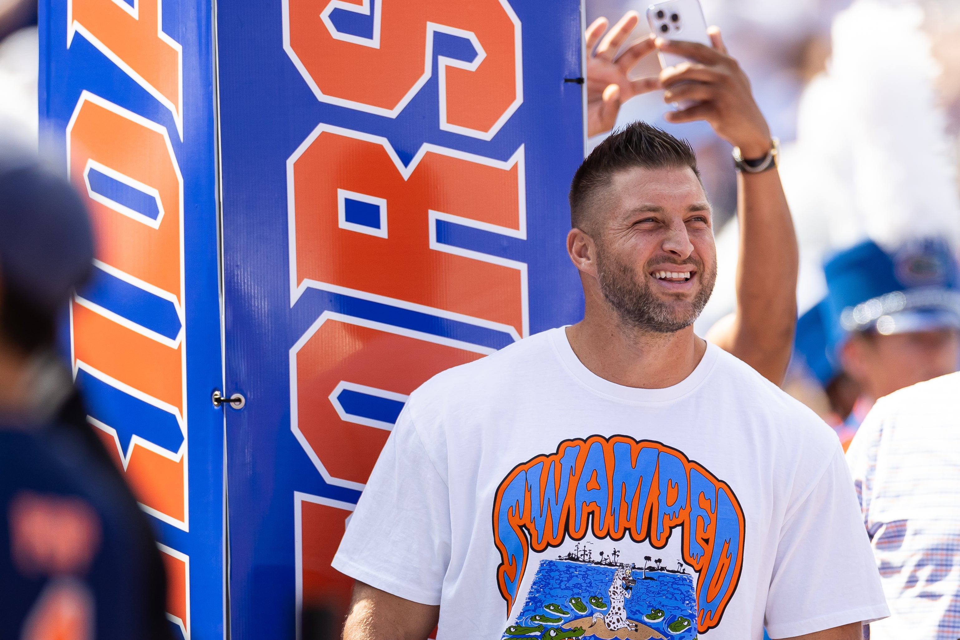 Aug 31, 2024; Gainesville, Florida, USA; Former Florida Gators quarterback Tim Tebow (15) watches team introductions against the Miami Hurricanes before the game at Ben Hill Griffin Stadium.