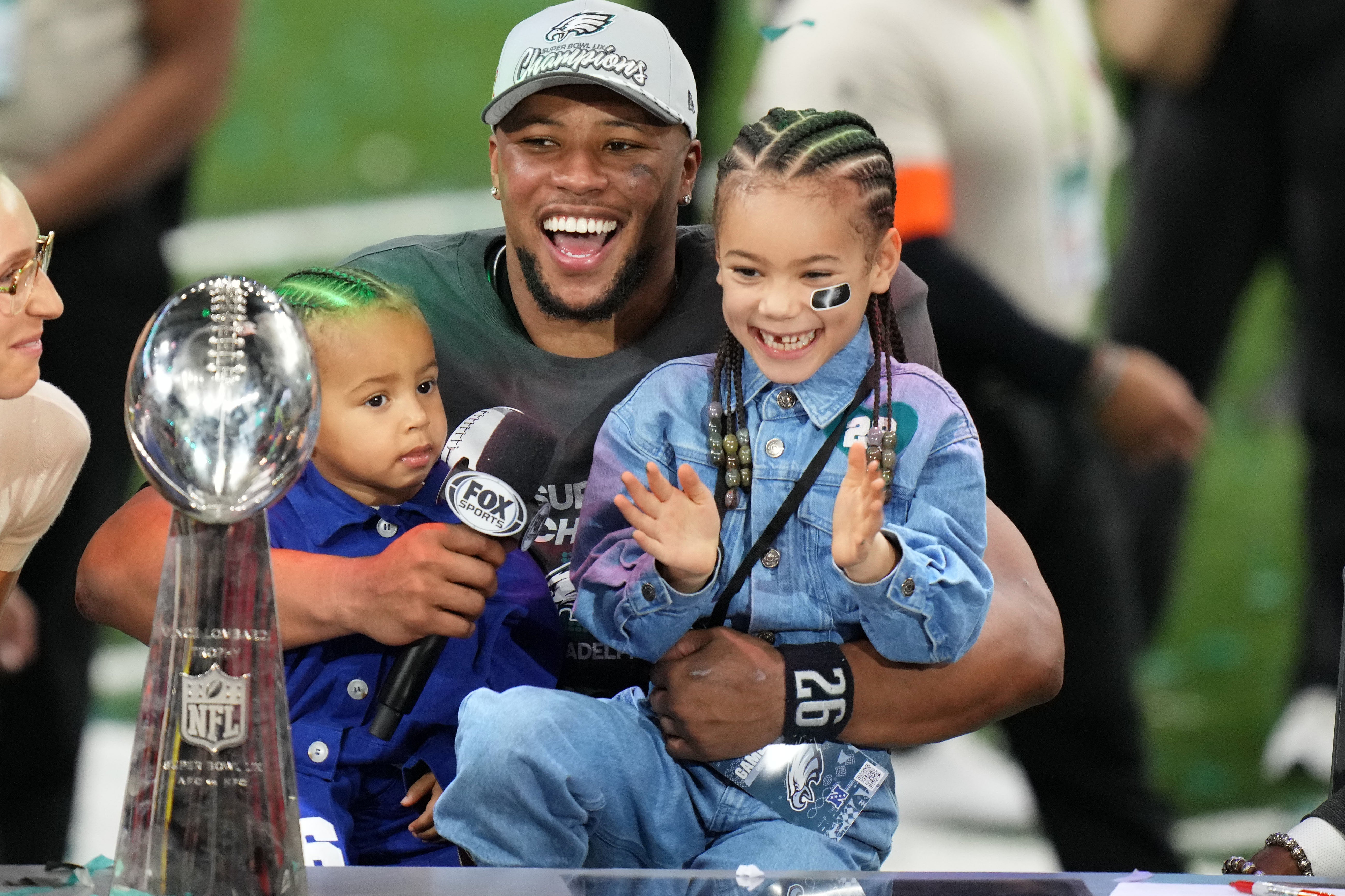 Philadelphia Eagles running back Saquon Barkley (26) talks to the media with his kids, Jada (right) and Saquon Jr. (left) after defeating the Kansas City Chiefs in Super Bowl LIX at Caesars Superdome.
