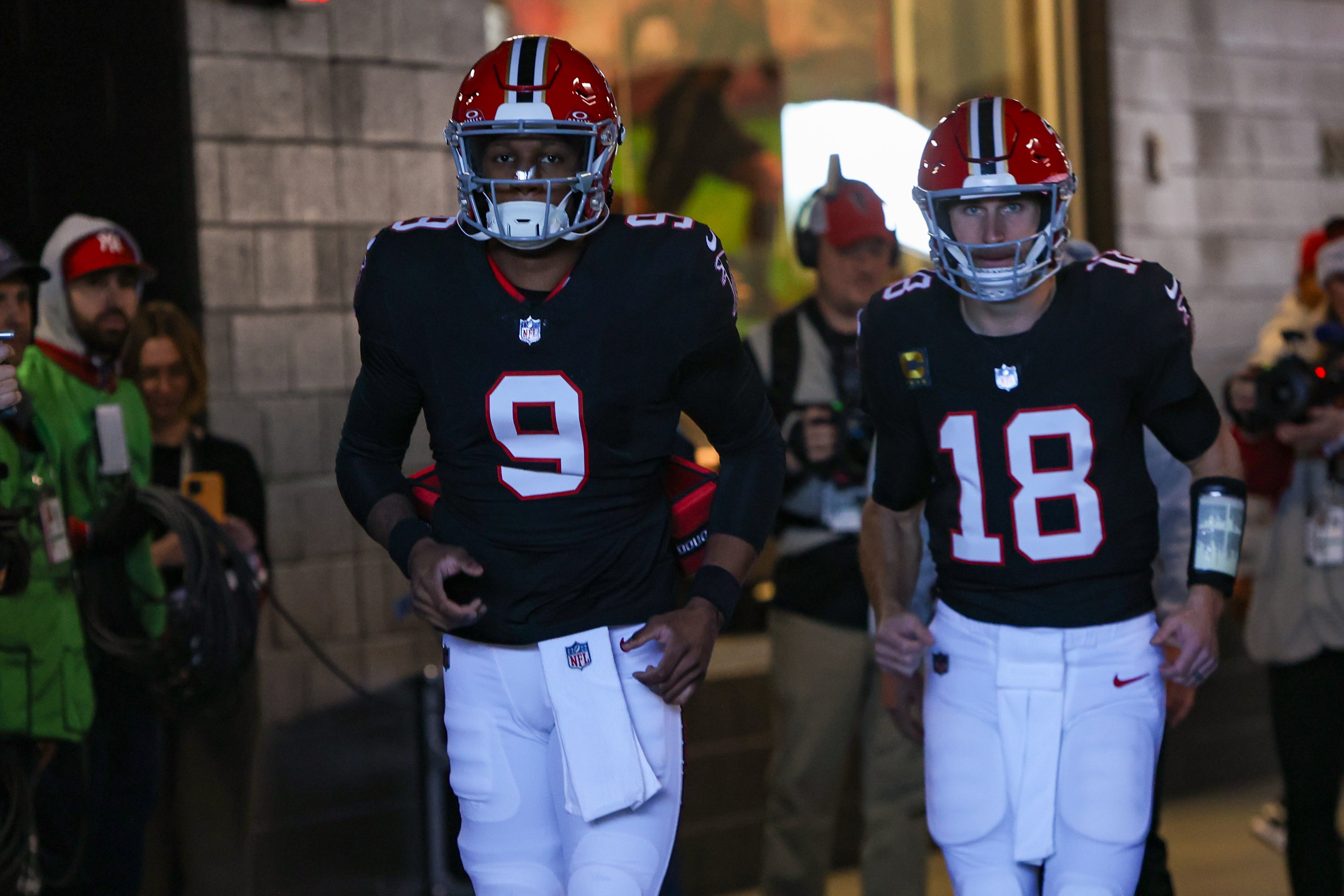 Atlanta Falcons quarterback Michael Penix Jr. (9) and quarterback Kirk Cousins (18) run on the field before a game against the New York Giants at Mercedes-Benz Stadium.