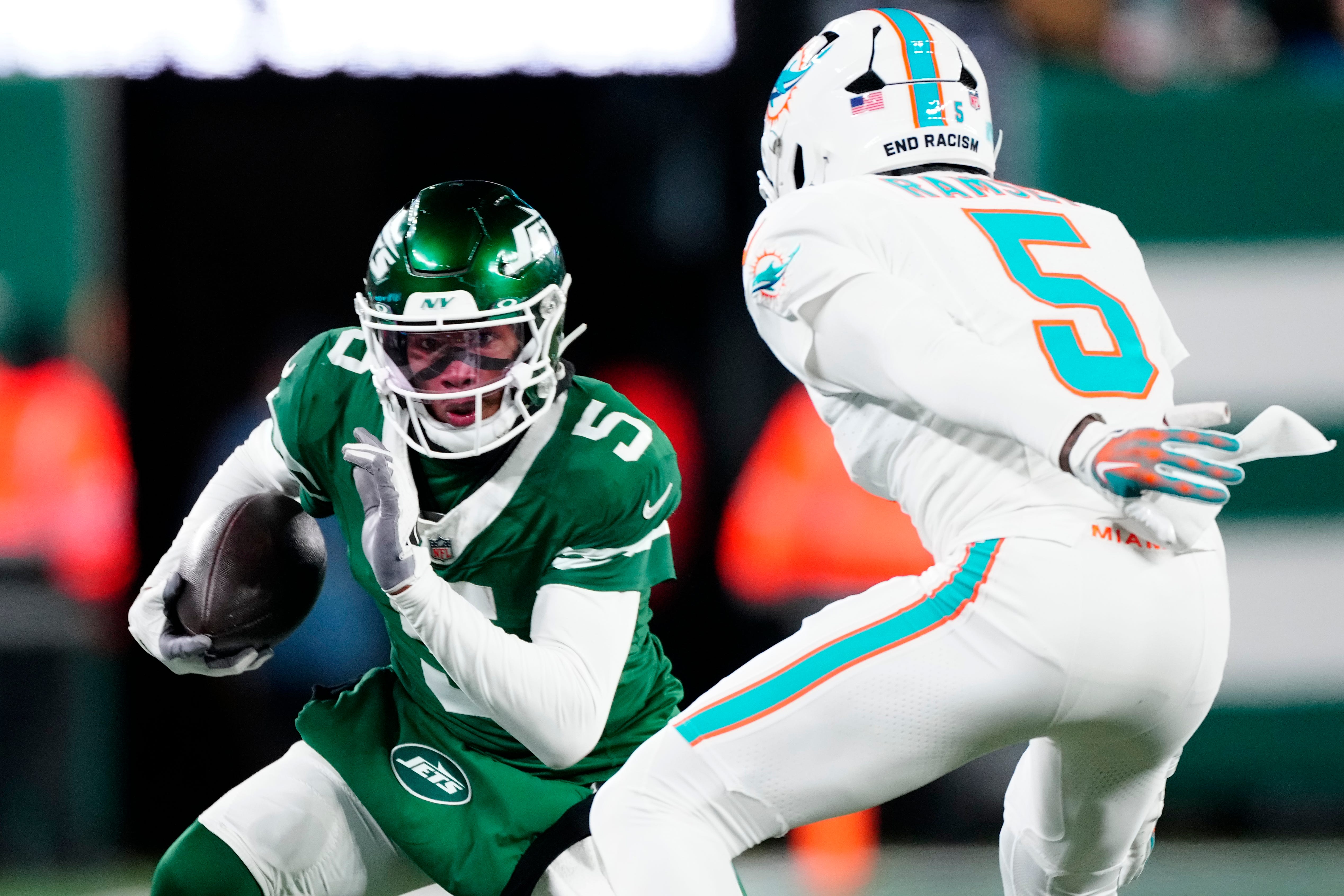 New York Jets wide receiver Garrett Wilson (5) runs with the ball as he tries to find a way past Miami Dolphins cornerback Jalen Ramsey (5), Sunday January 5, 2025, in East Rutherford.