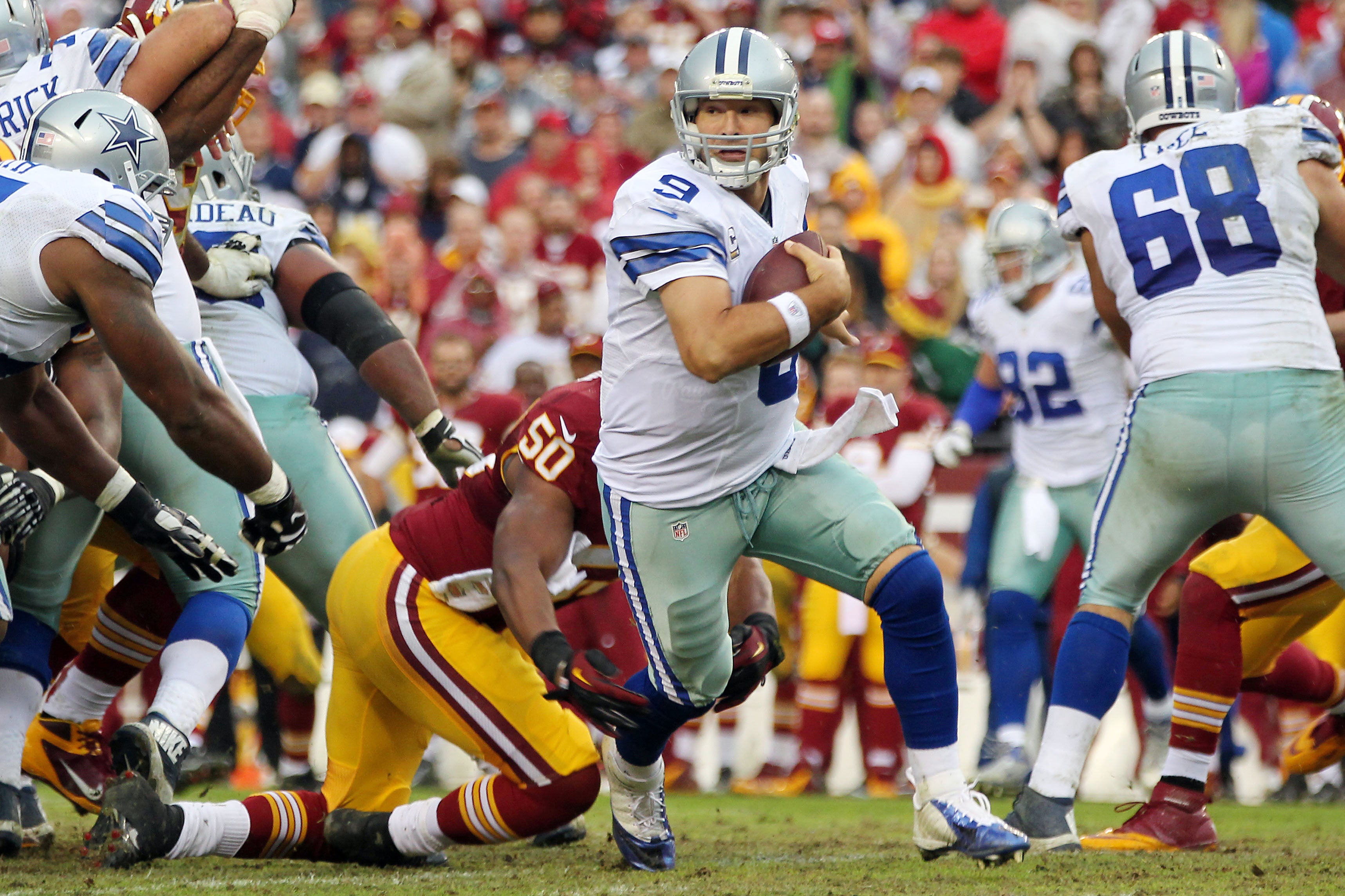 Dallas Cowboys quarterback Tony Romo (9) scrambles from Washington Redskins outside linebacker Rob Jackson (50) in the fourth quarter at FedEx Field. Romo was injured on the play and is out for the season. The Cowboys won 24-23.