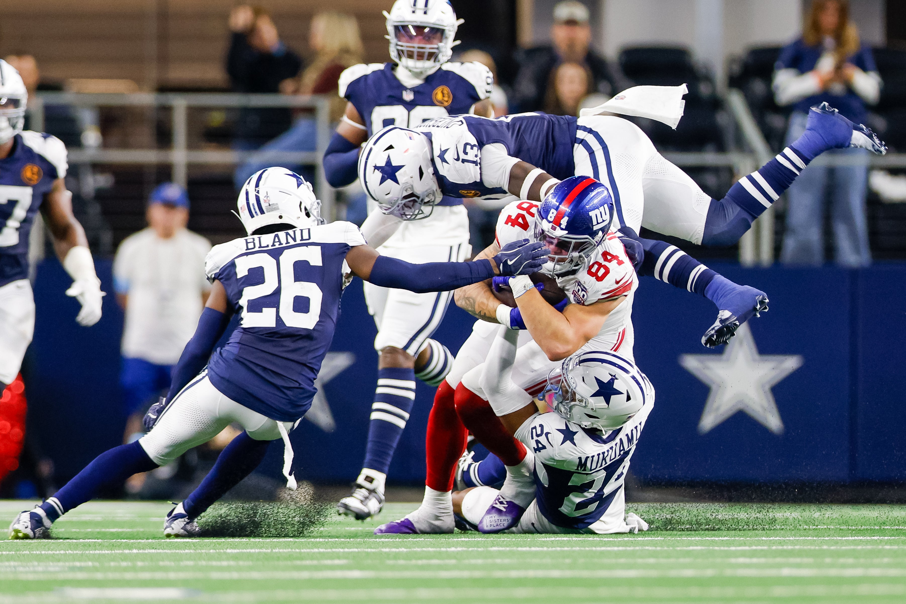 New York Giants tight end Theo Johnson (84) is tackled by Dallas Cowboys safety Israel Mukuamu (24), linebacker DeMarvion Overshown (13) and cornerback DaRon Bland (26) during the fourth quarter at AT&T Stadium.