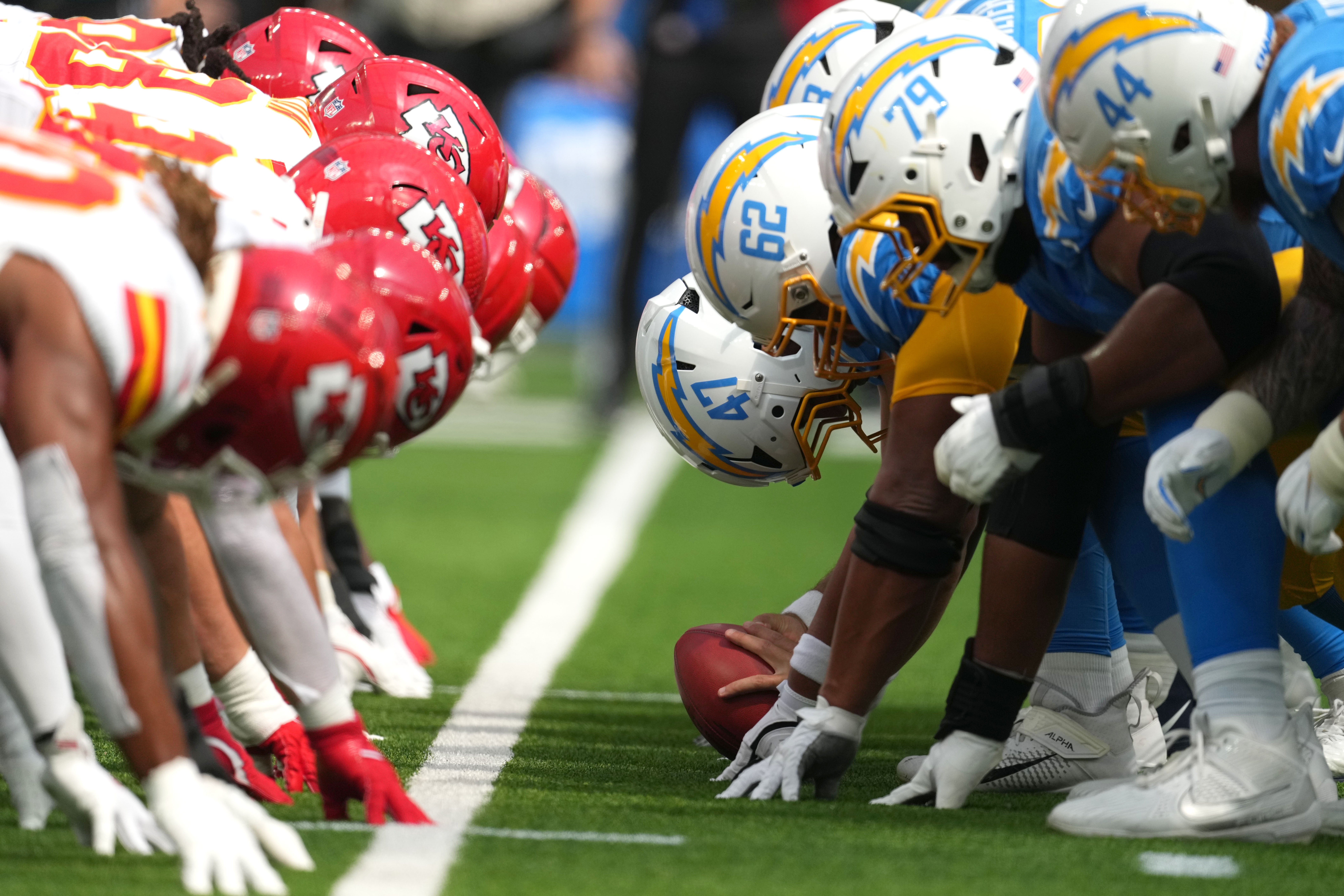 Kansas City Chiefs and Los Angeles Chargers helmets at the line of scrimmage as Chargers long snapper Josh Harris (47) snaps the ball at SoFi Stadium.