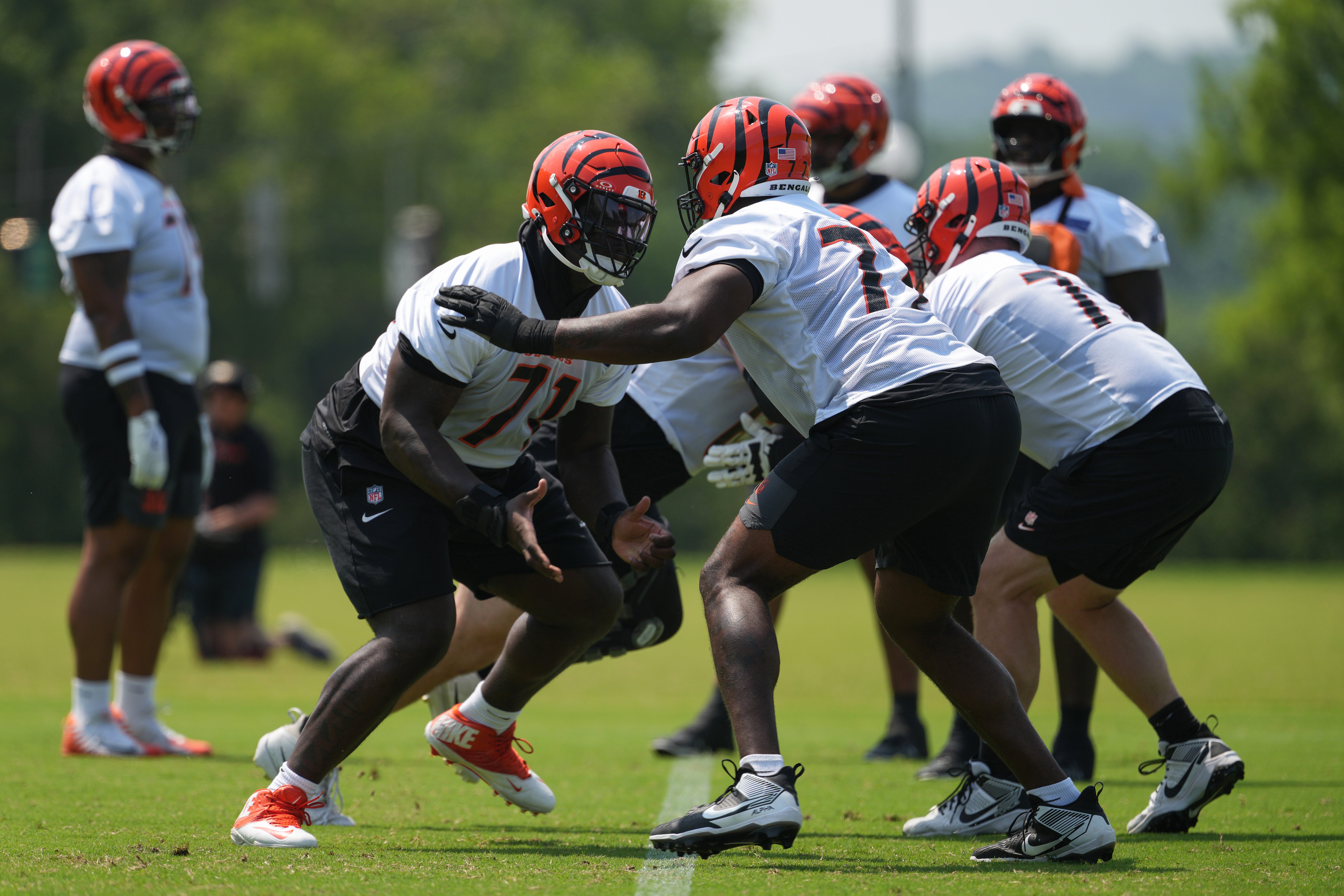 Jun 10, 2025; Cincinnati, OH, USA; Cincinnati Bengals offensive tackle Amarius Mims (71) (center) blocks against offensive tackle Caleb Etienne (77) (right) during practice at Paycor Stadium.