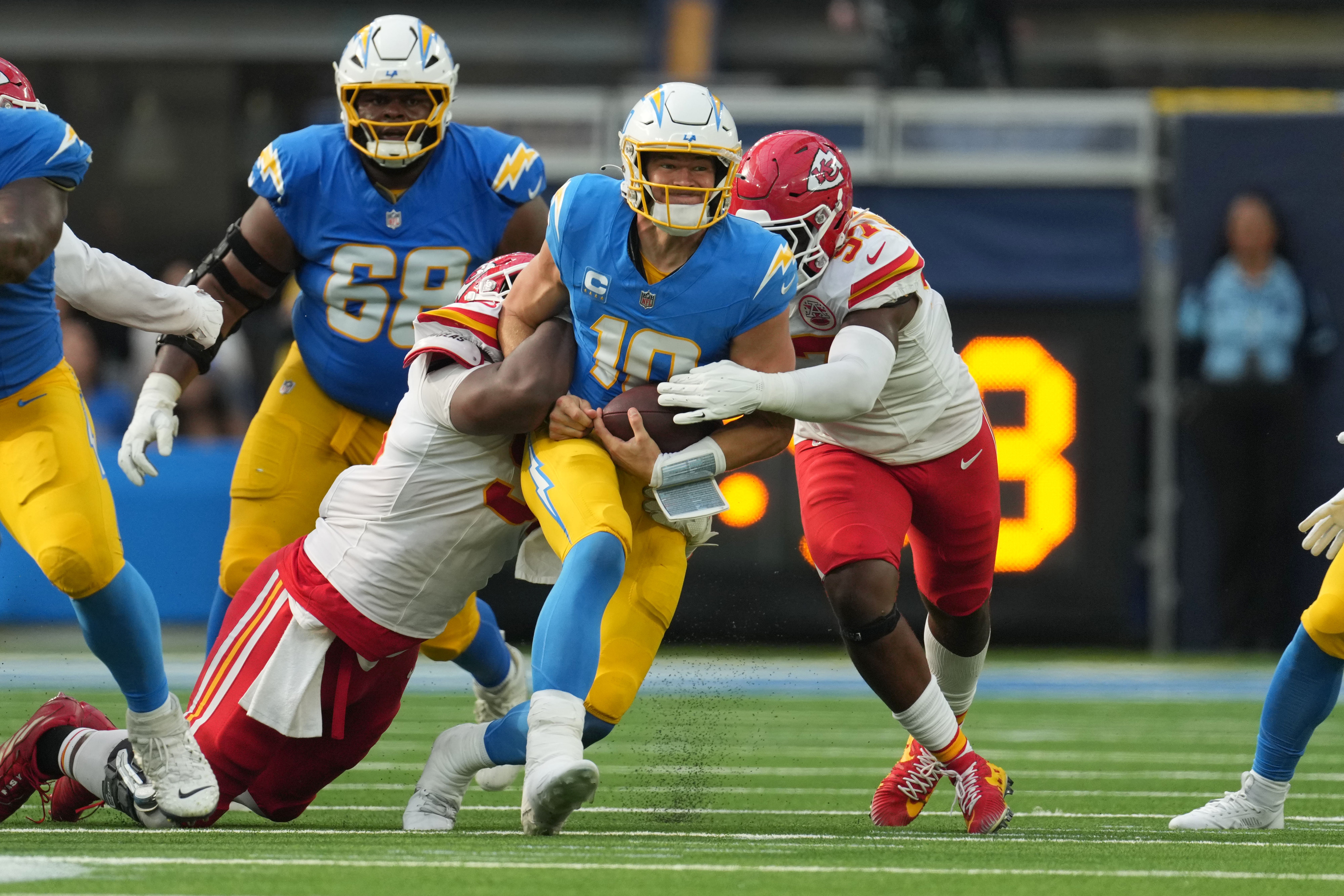 Los Angeles Chargers quarterback Justin Herbert (10) is tackled by Kansas City Chiefs defensive tackle Chris Jones (95) and defensive end Felix Anudike-Uzomah (97) in the second half at SoFi Stadium.