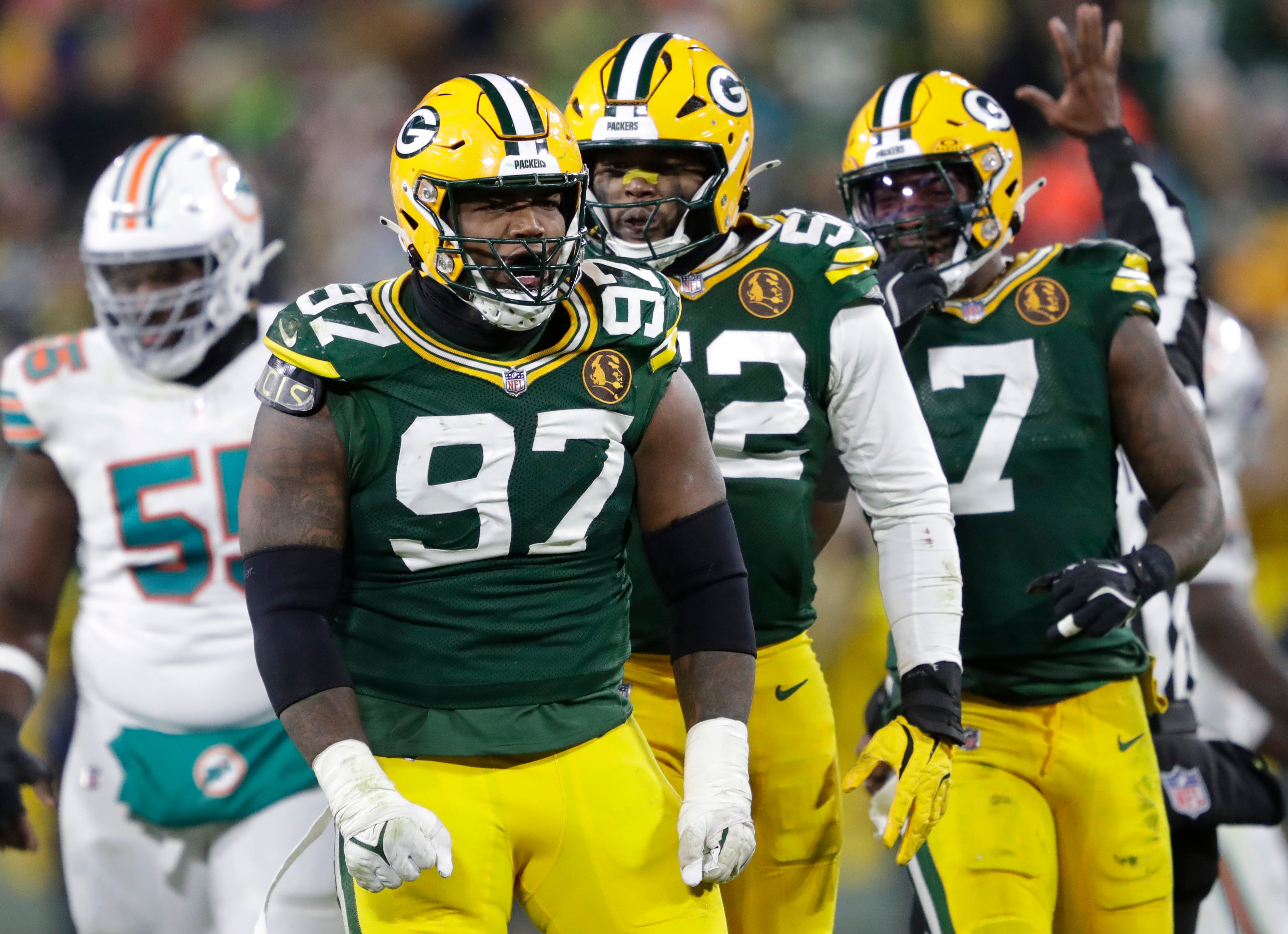 Green Bay Packers defensive tackle Kenny Clark (97) celebrates sacking Miami Dolphins quarterback Tua Tagovailoa with defensive end Rashan Gary (52) and linebacker Quay Walker (7) at Lambeau Field.