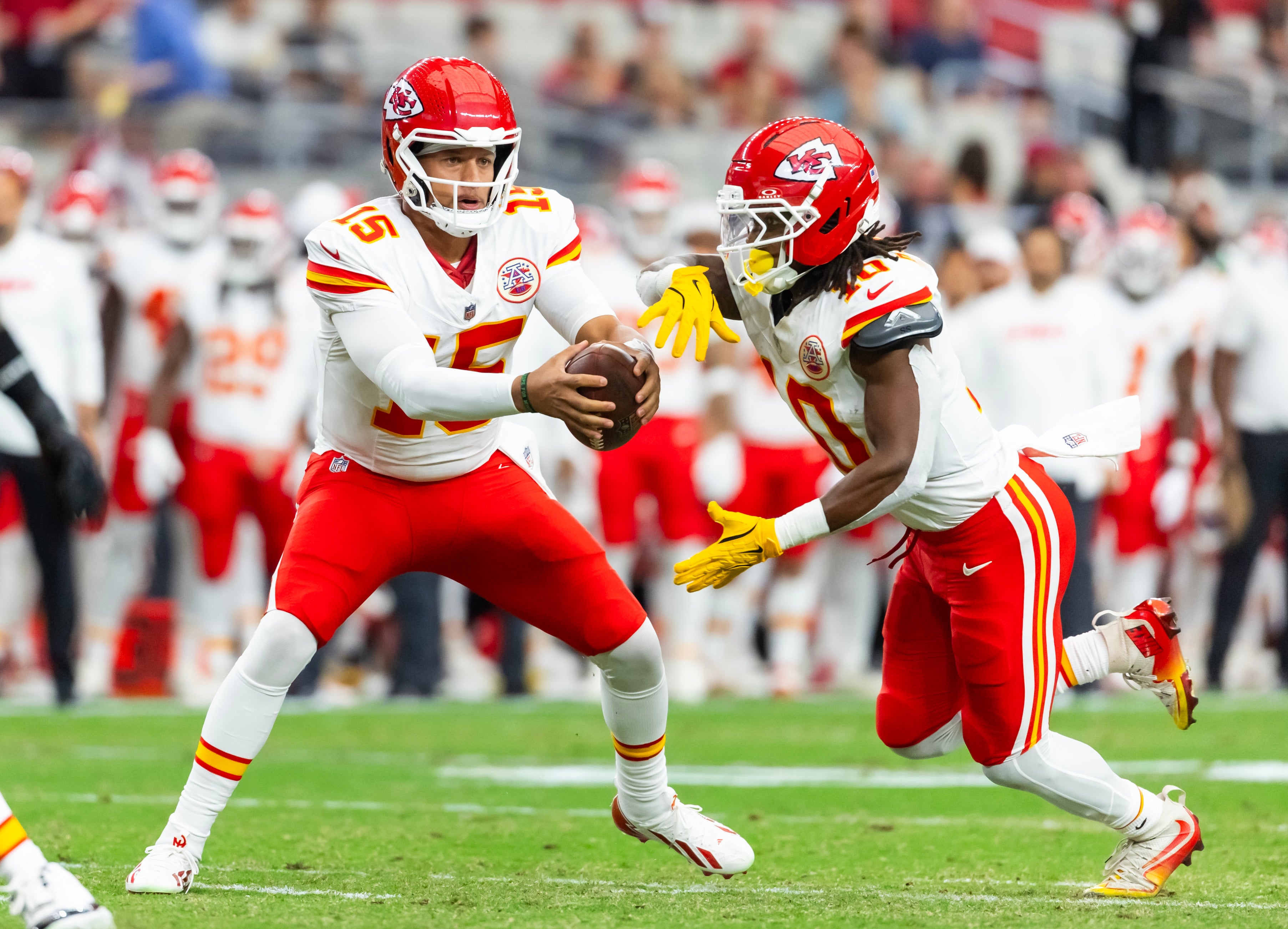 Kansas City Chiefs quarterback Patrick Mahomes (15) fakes a handoff to running back Isiah Pacheco (10) against the Arizona Cardinals during a preseason NFL game at State Farm Stadium.