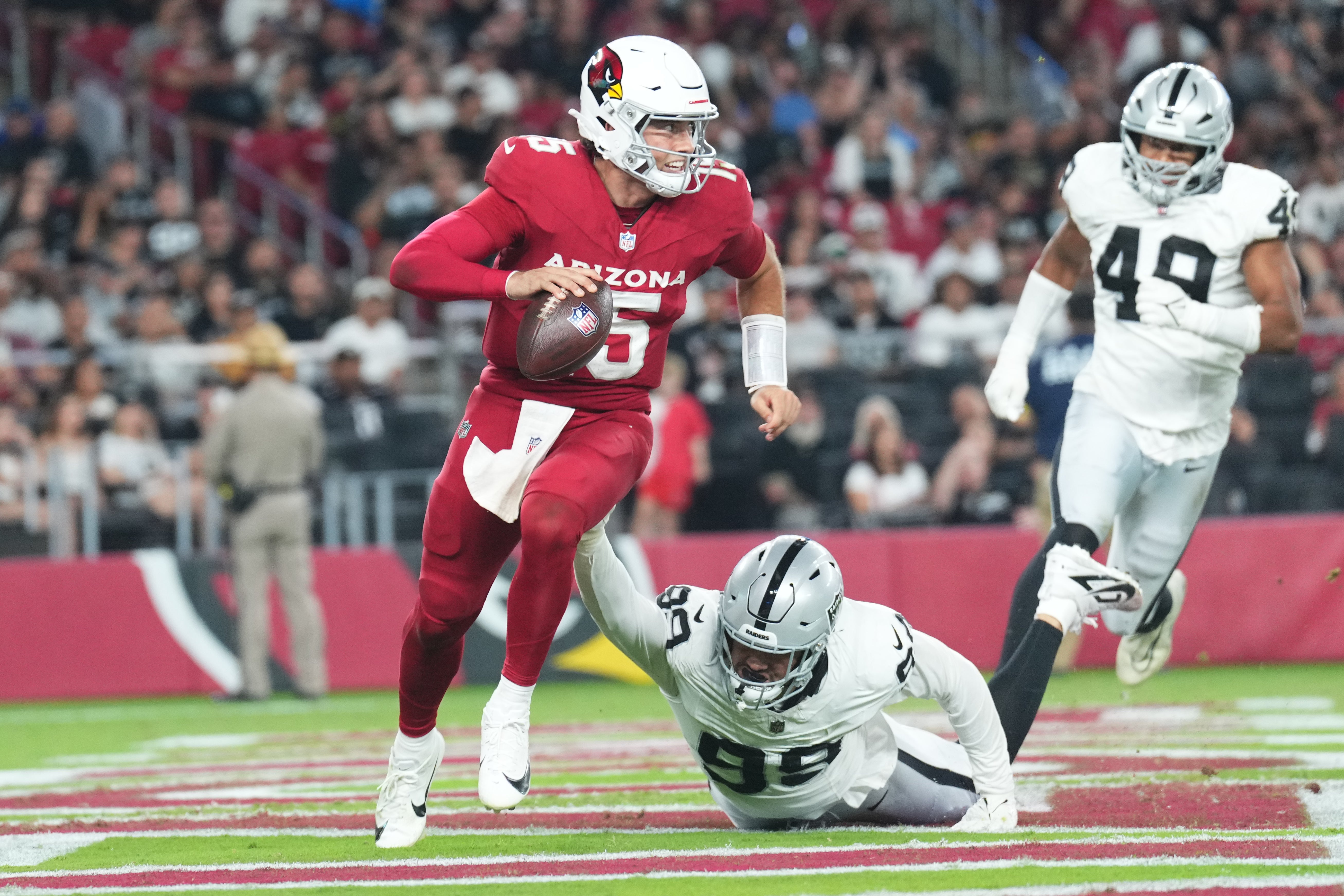 Aug 23, 2025; Glendale, Arizona, USA; Arizona Cardinals quarterback Clayton Tune (15) runs by Las Vegas Raiders defensive end Andre Carter II (99) during the second half at State Farm Stadium.