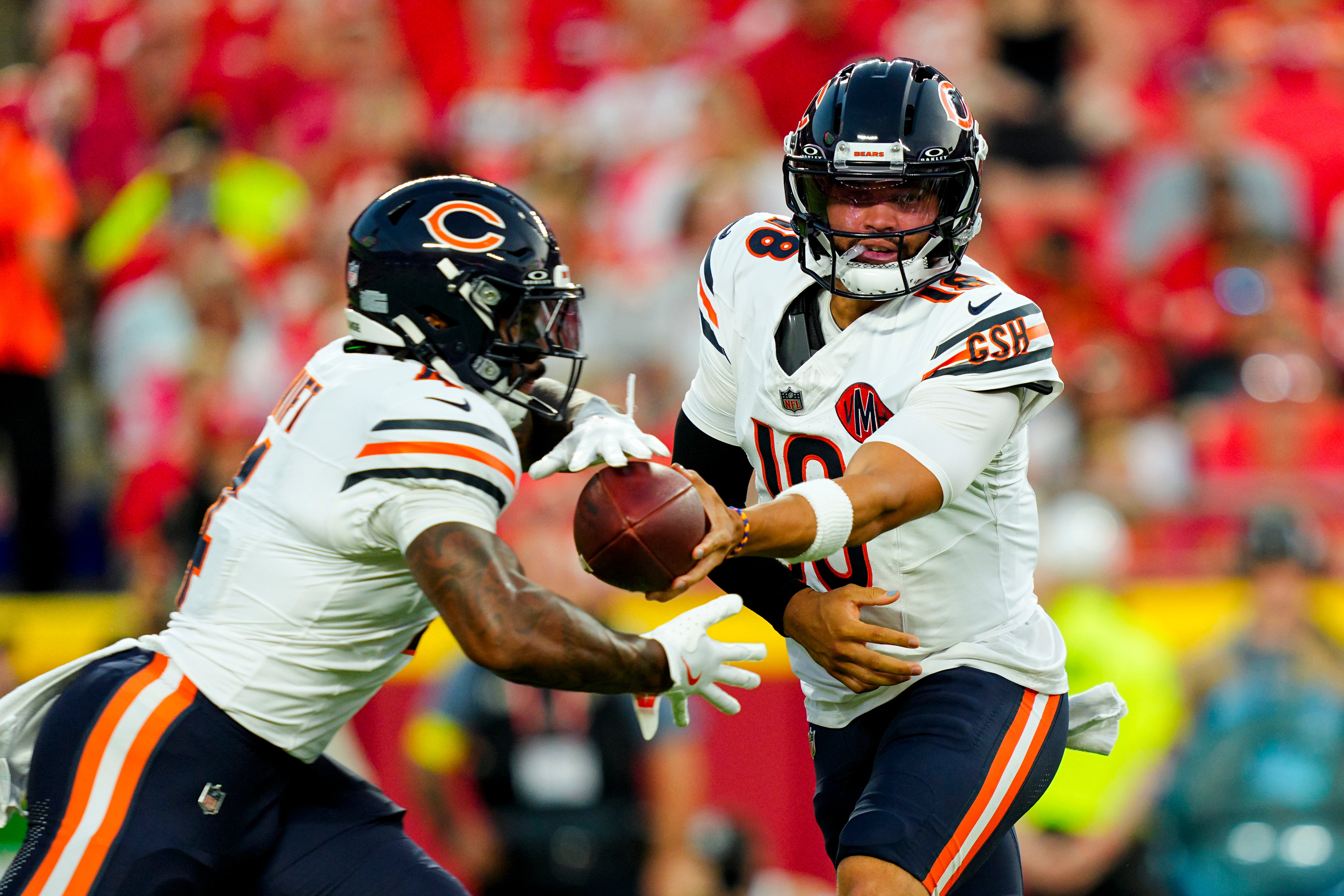Aug 22, 2025; Kansas City, Missouri, USA; Chicago Bears quarterback Caleb Williams (18) hands off to running back D'Andre Swift (4) during the first half against the Kansas City Chiefs at GEHA Field at Arrowhead Stadium.