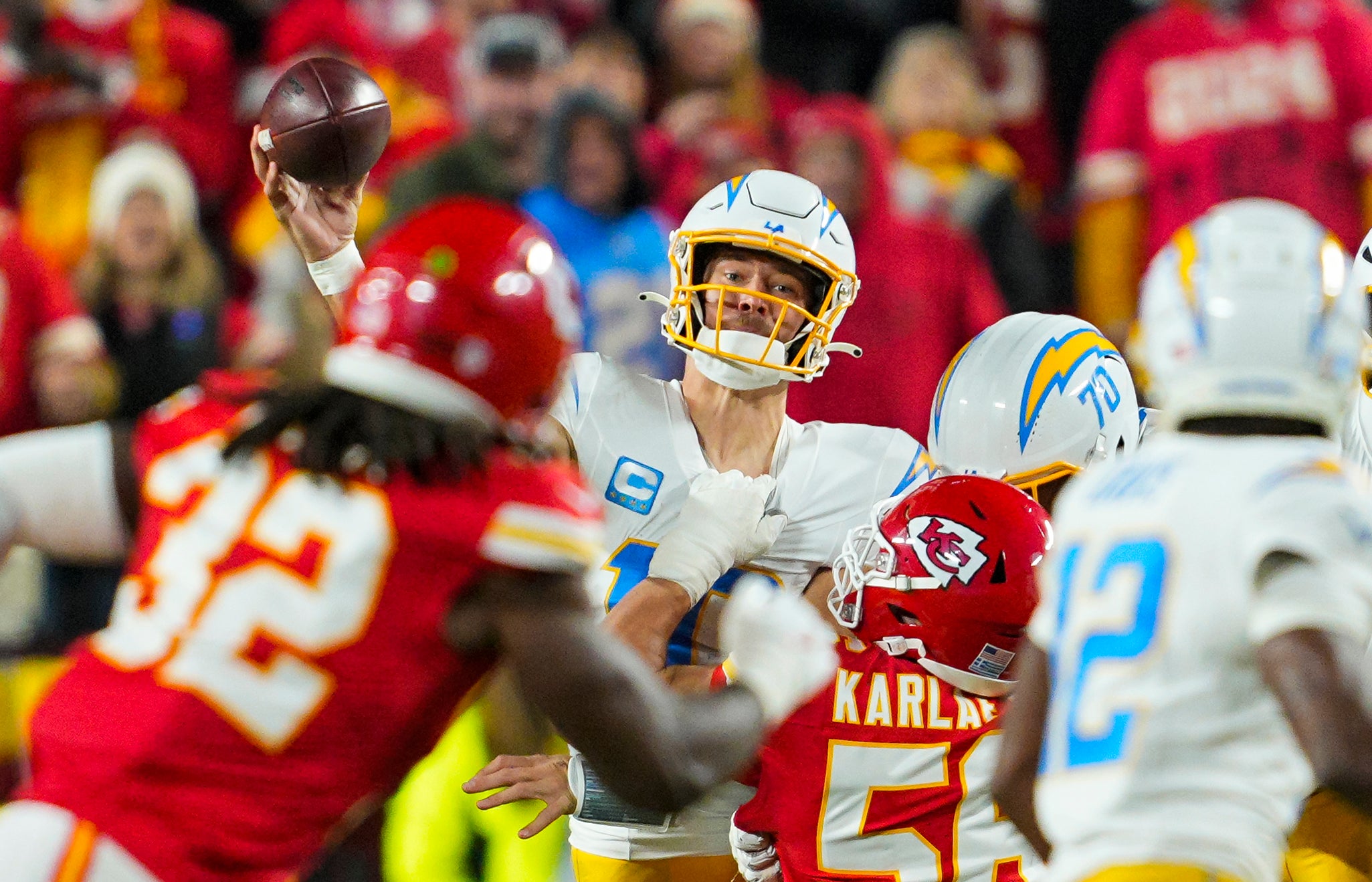 Los Angeles Chargers quarterback Justin Herbert (10) throws a pass as he is hit by Kansas City Chiefs defensive end George Karlaftis (56) during the first half at GEHA Field at Arrowhead Stadium.