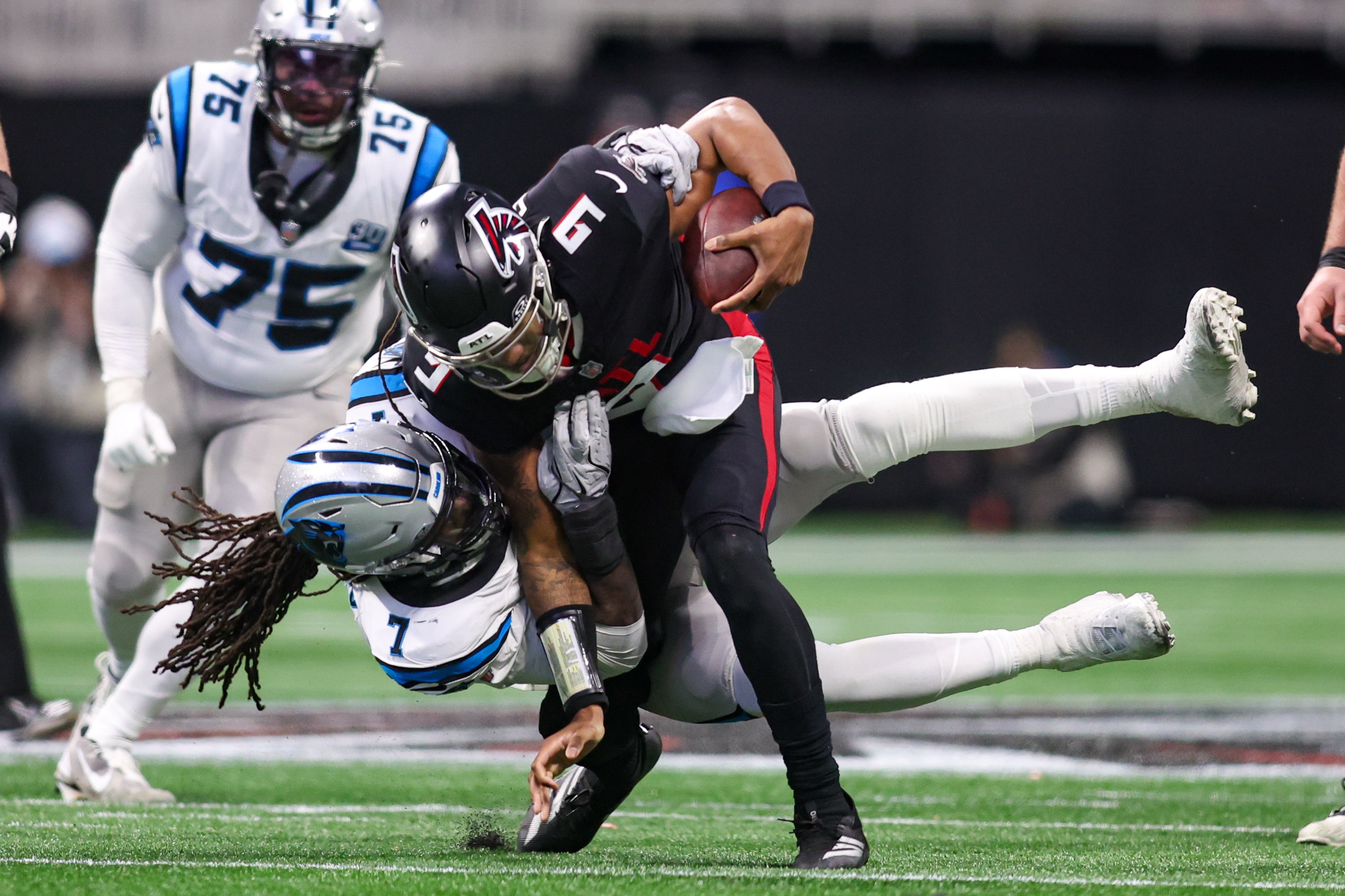 Carolina Panthers linebacker Jadeveon Clowney (7) tackles Atlanta Falcons quarterback Michael Penix Jr. (9) in the third quarter at Mercedes-Benz Stadium.