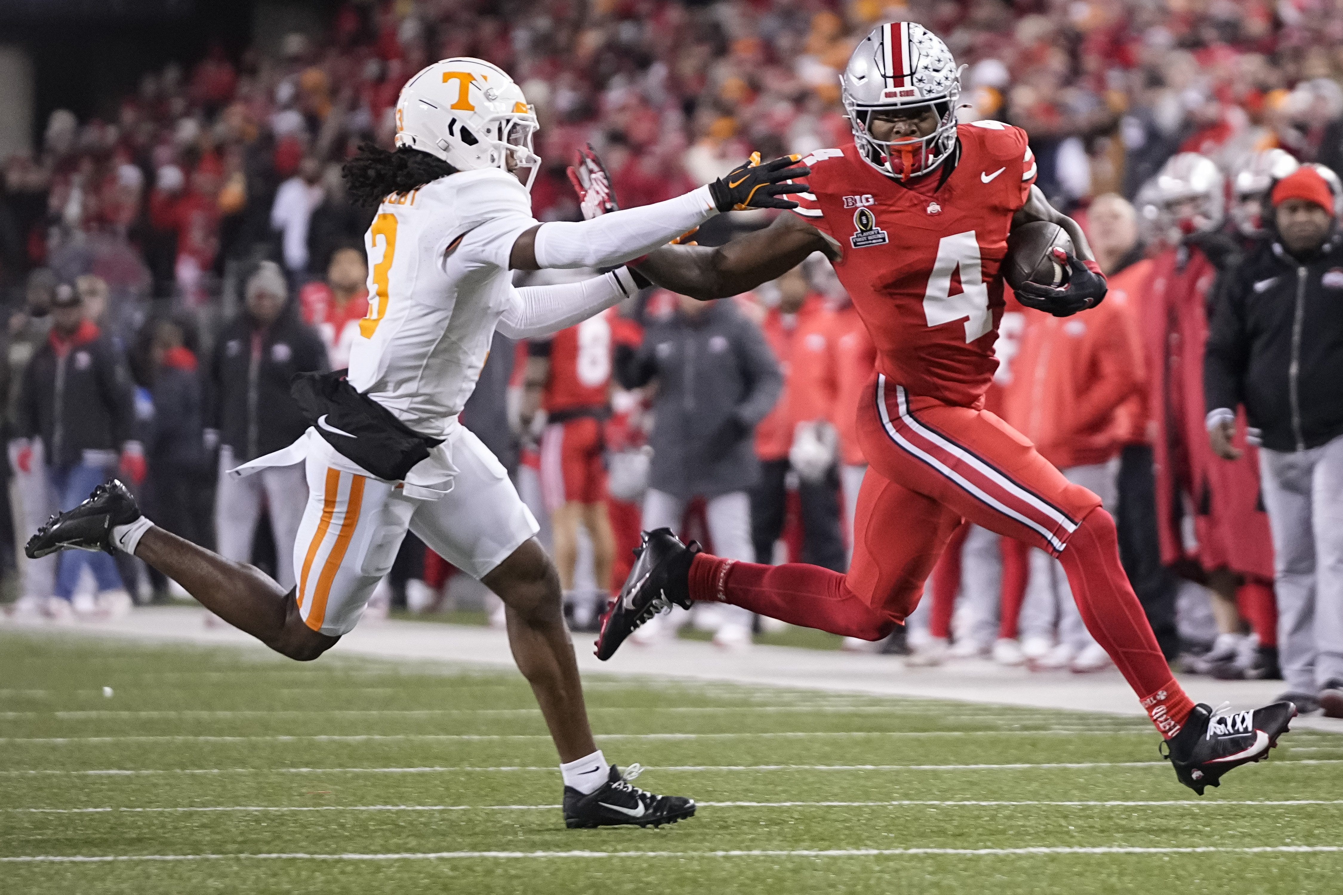 Ohio State Buckeyes wide receiver Jeremiah Smith (4) runs past Tennessee Volunteers defensive back Jermod McCoy (3) during the first half of the College Football Playoff first round game at Ohio Stadium in Columbus on Dec. 21, 2024.