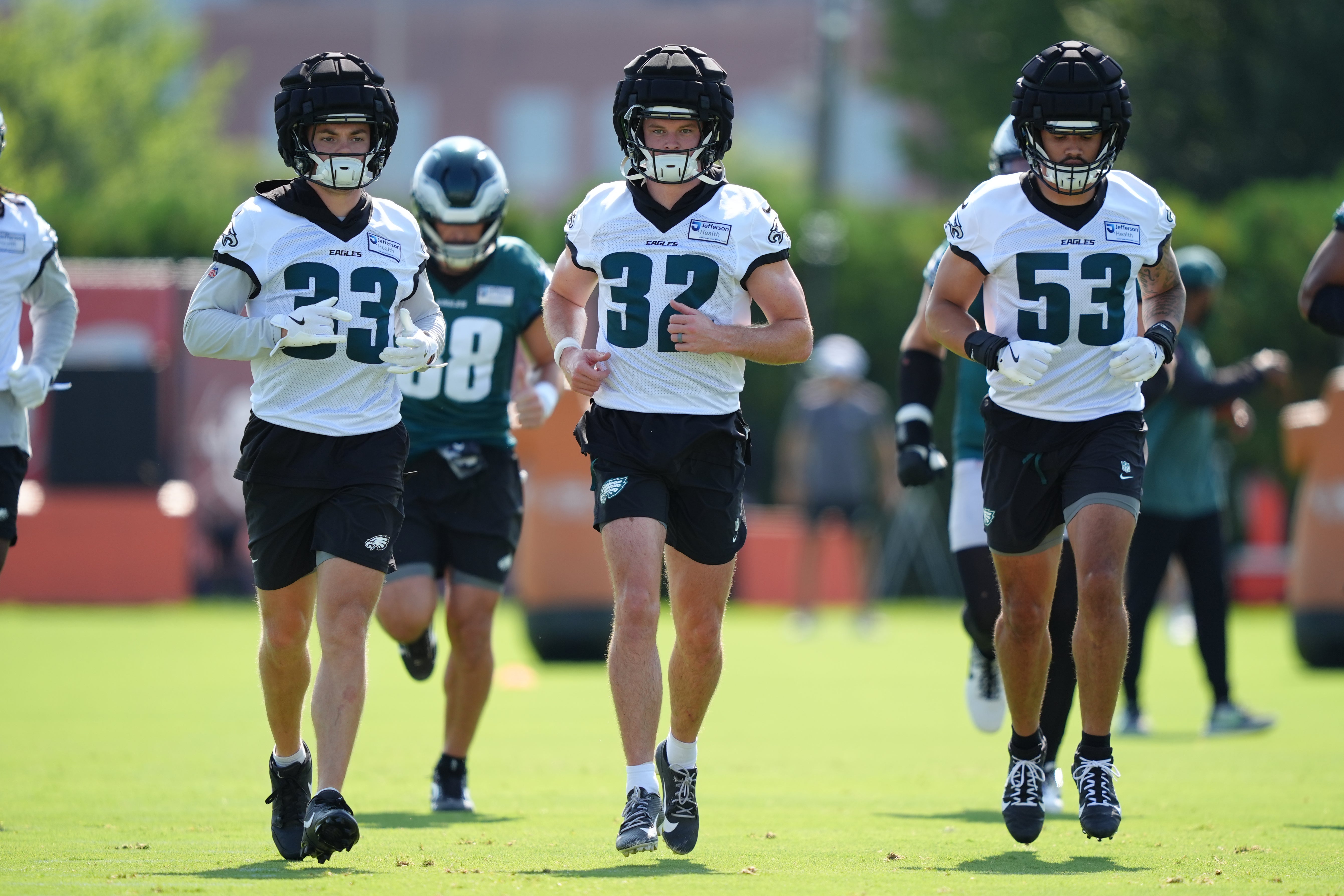Philadelphia Eagles defensive back Cooper DeJean (33), safety Reed Blankenship (32), and linebacker Zack Baun (53) warm up during training camp at NovaCare Complex.