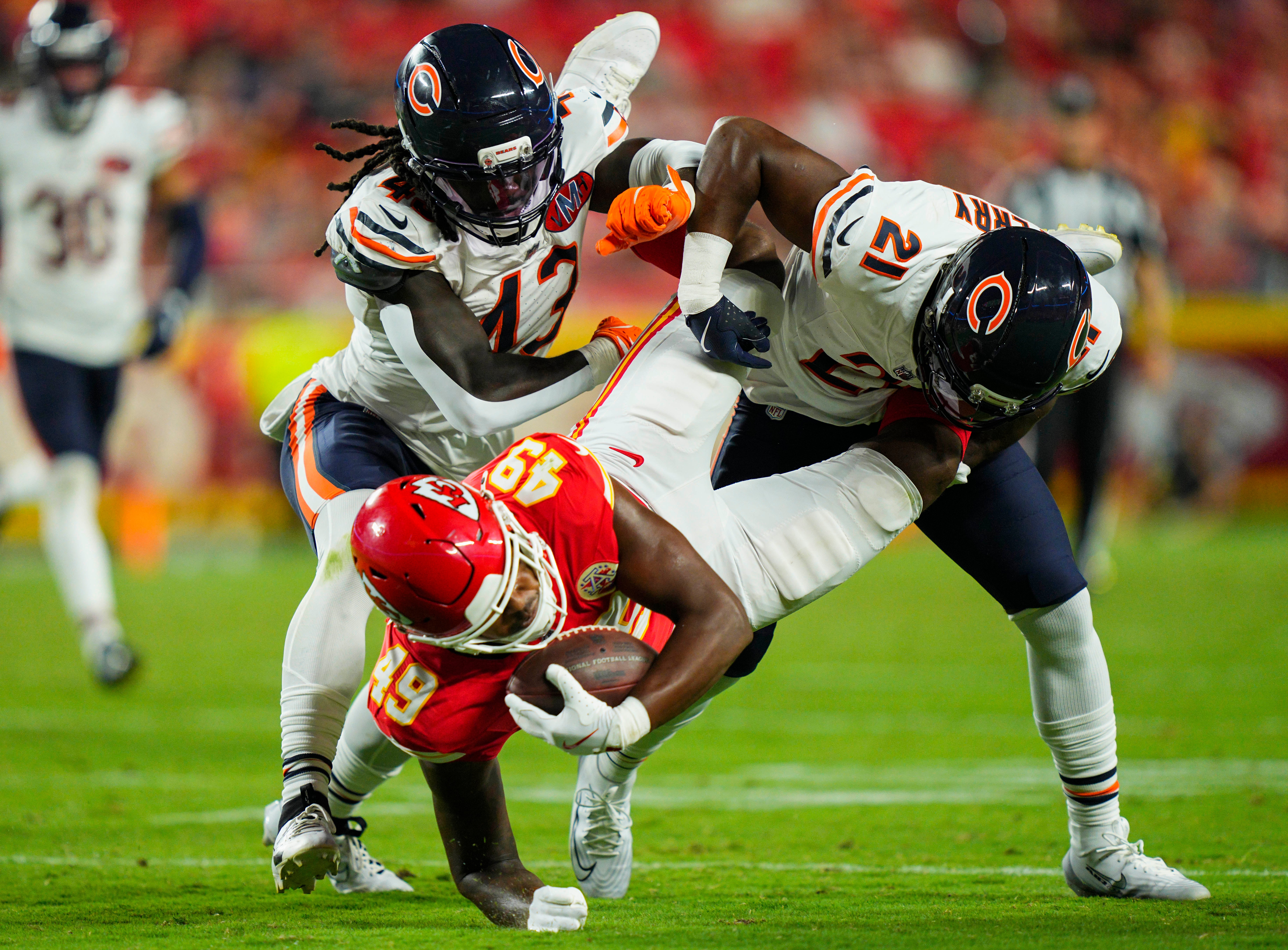 Aug 22, 2025; Kansas City, Missouri, USA; Kansas City Chiefs tight end Tre Watson (49) is tackled by Chicago Bears linebacker Carl Jones (43) and Chicago Bears safety Mark Perry (21) during the second half at GEHA Field at Arrowhead Stadium.