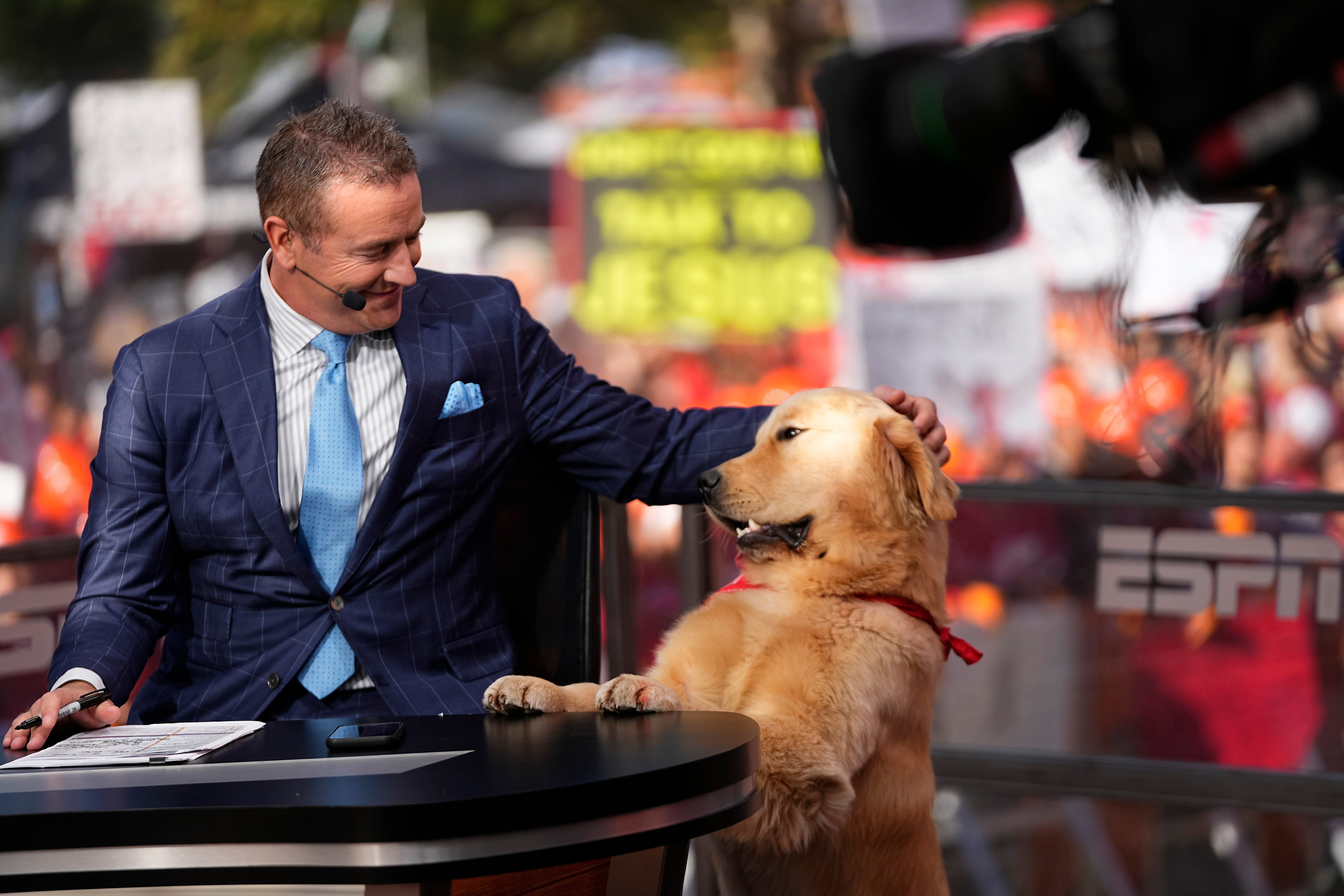 Kirk Herbstreit pets his dog, Peter, on the set of ESPN College GameDay