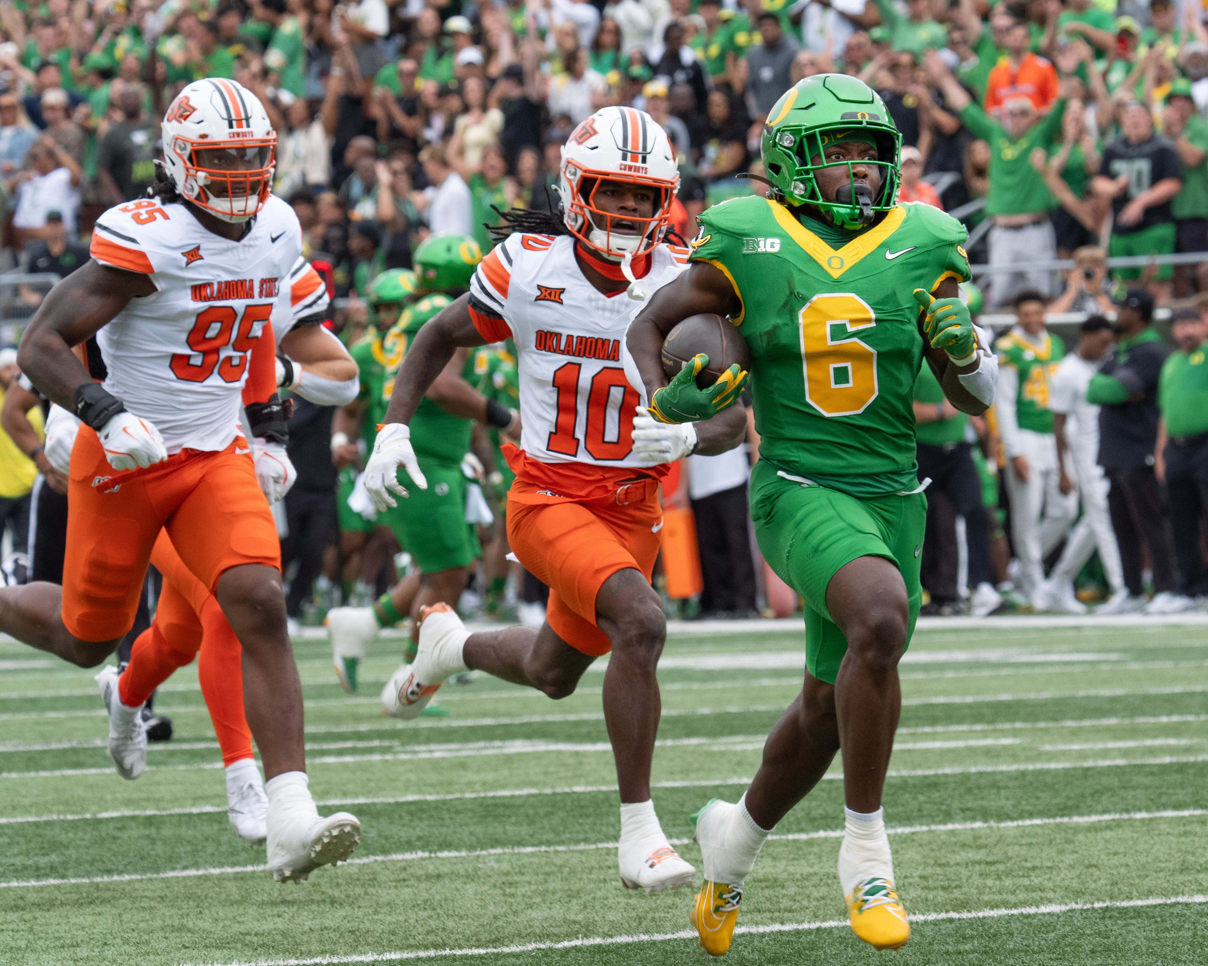 Oregon’s Noah Whittington, right, break for the end zone for the first touchdown of the game against Oklahoma State during the first quarter at Autzen.