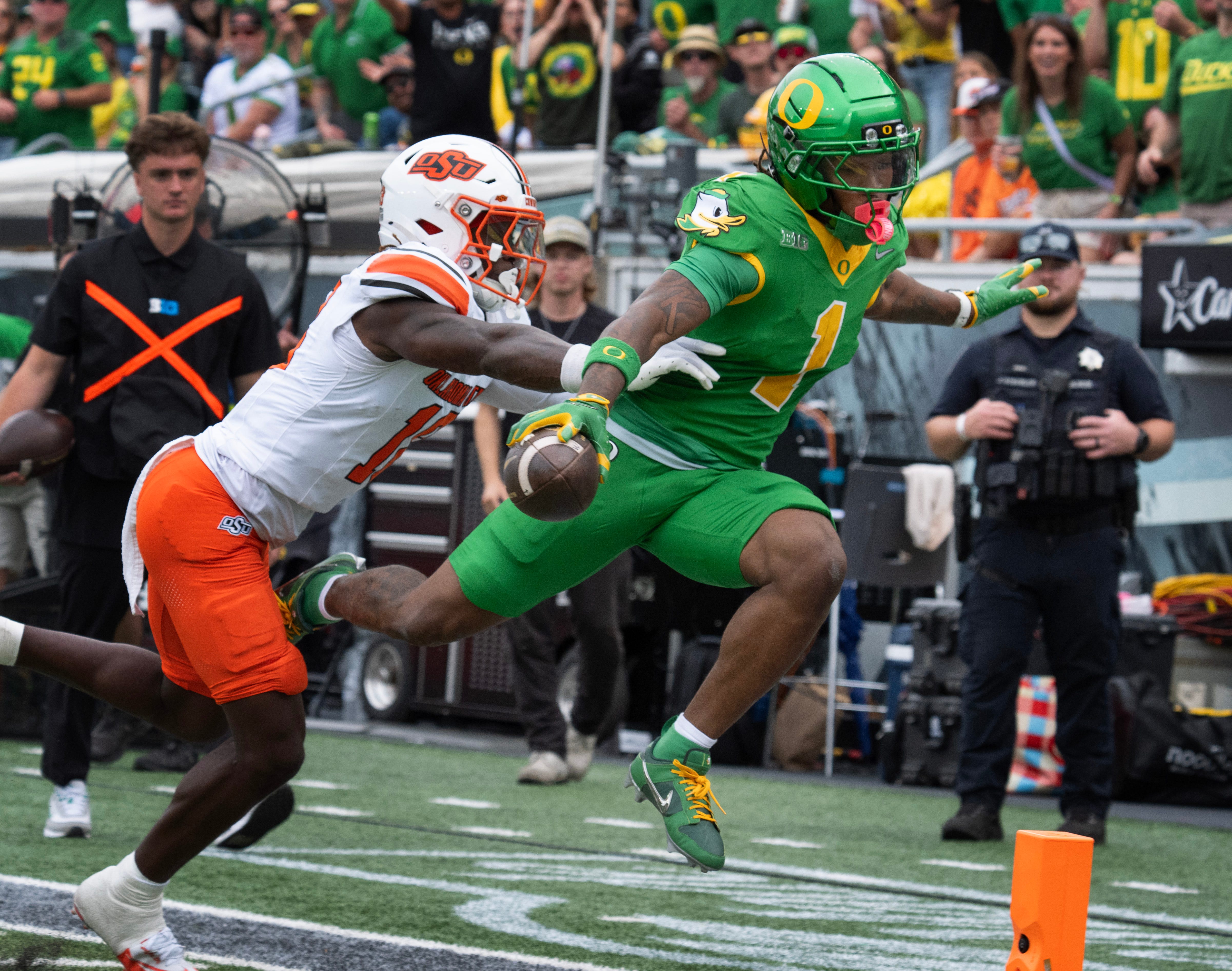 Oregon’s Dakorien Moore, right, flies over the goal line ahead of Oklahoma State’s David Kabongo for a second quarter touchdown at Autzen.