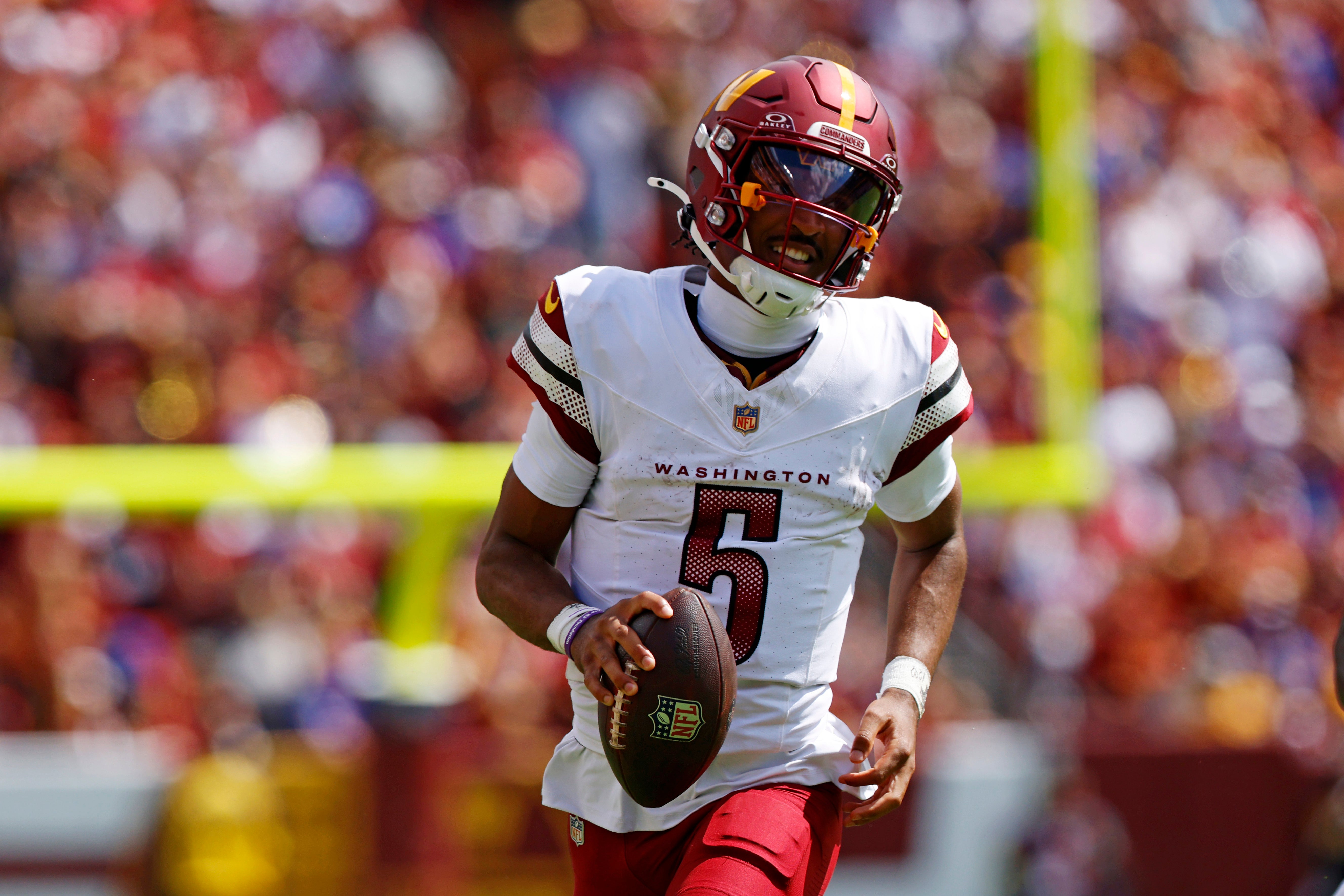 Sep 7, 2025; Landover, Maryland, USA; Washington Commanders quarterback Jayden Daniels (5) runs the ball against New York Giants linebacker Brian Burns (0) during the second quarter at Northwest Stadium.