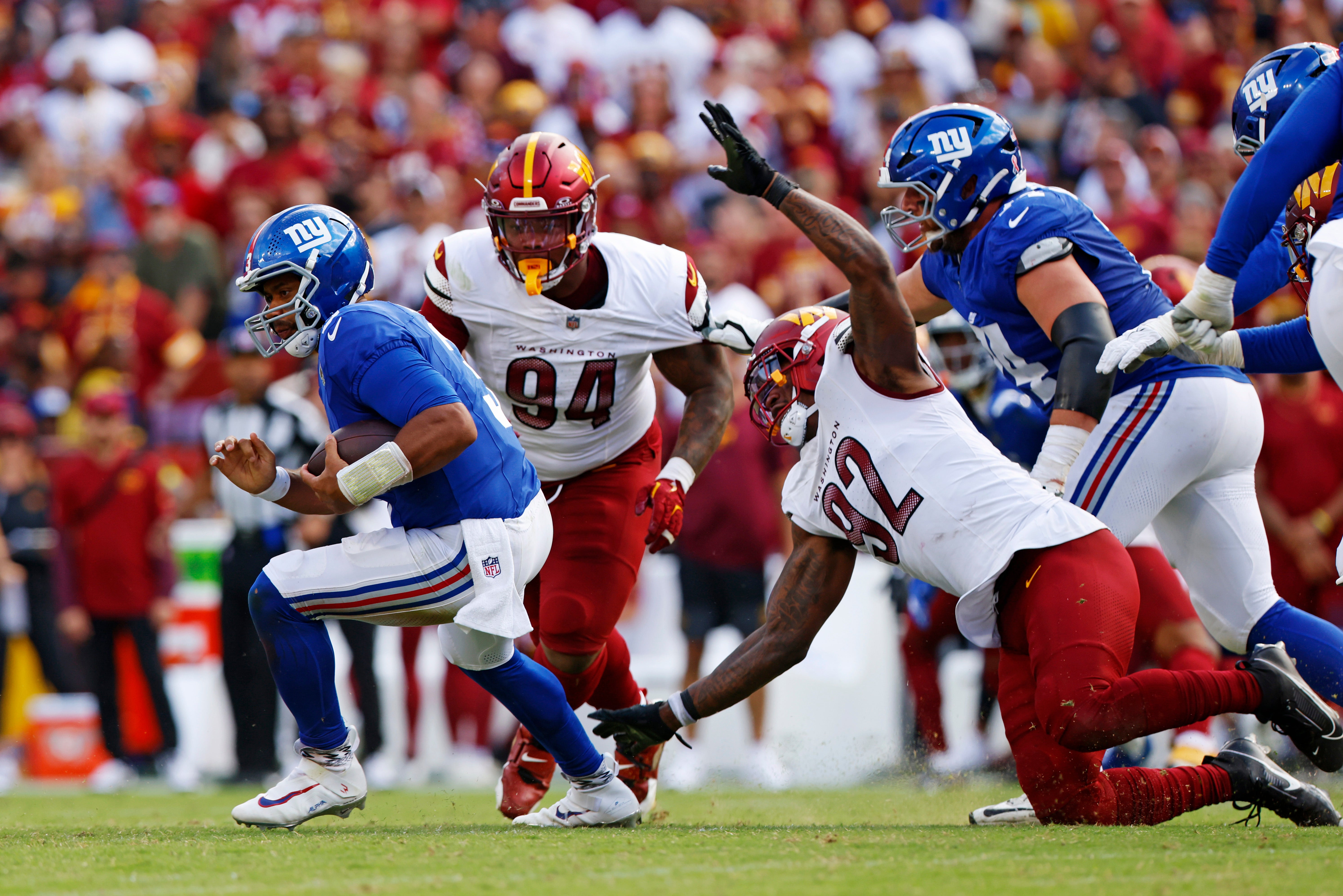Sep 7, 2025; Landover, Maryland, USA; New York Giants quarterback Russell Wilson (3) runs away from Washington Commanders defensive end Dorance Armstrong (92) during the fourth quarter at Northwest Stadium.