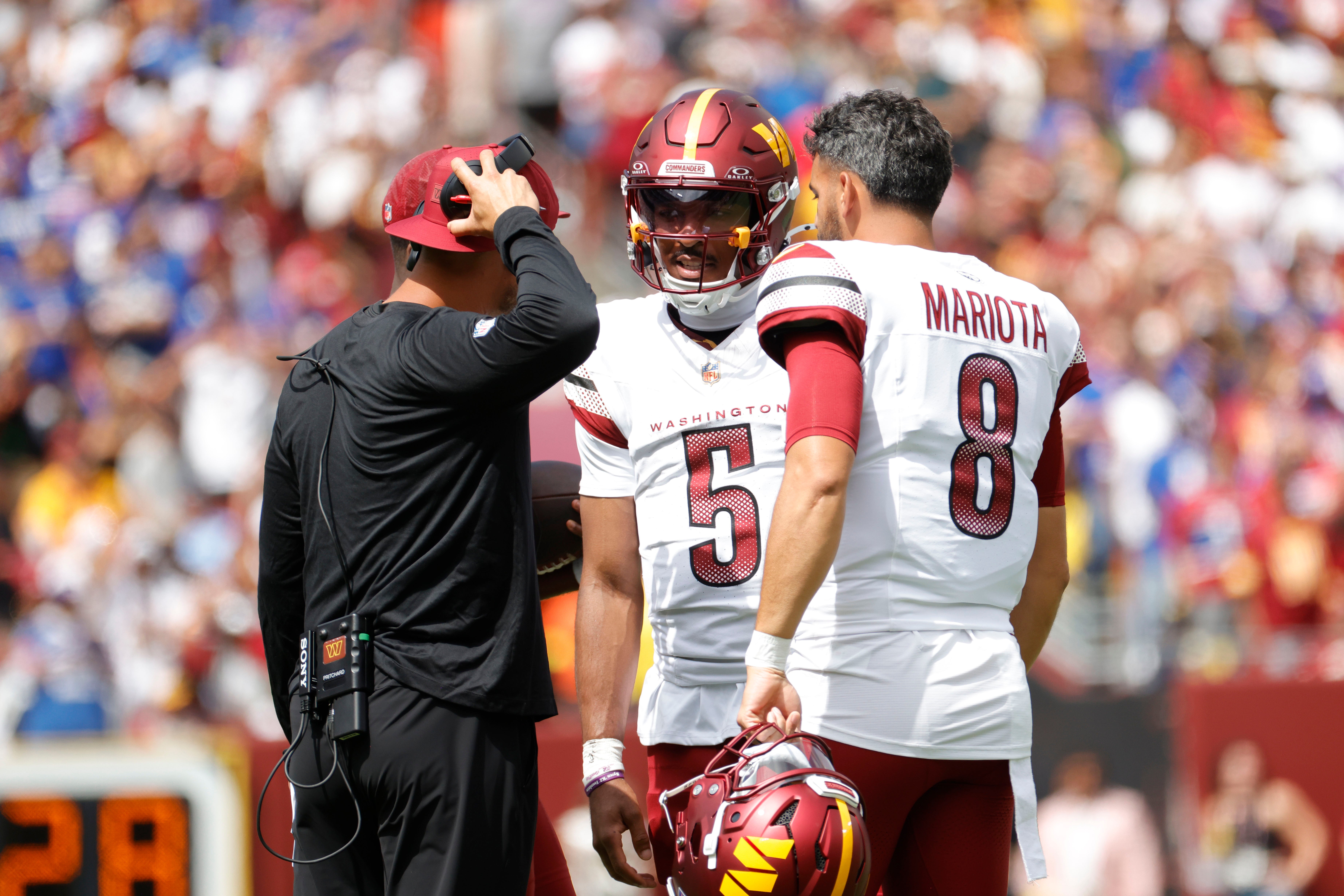 Sep 7, 2025; Landover, Maryland, USA; Washington Commanders quarterback Jayden Daniels (5) and Commanders quarterback Marcus Mariota (8) look on the field during the first quarter against the New York Giants at Northwest Stadium. Mandatory Credit: Amber Searls-Imagn Images