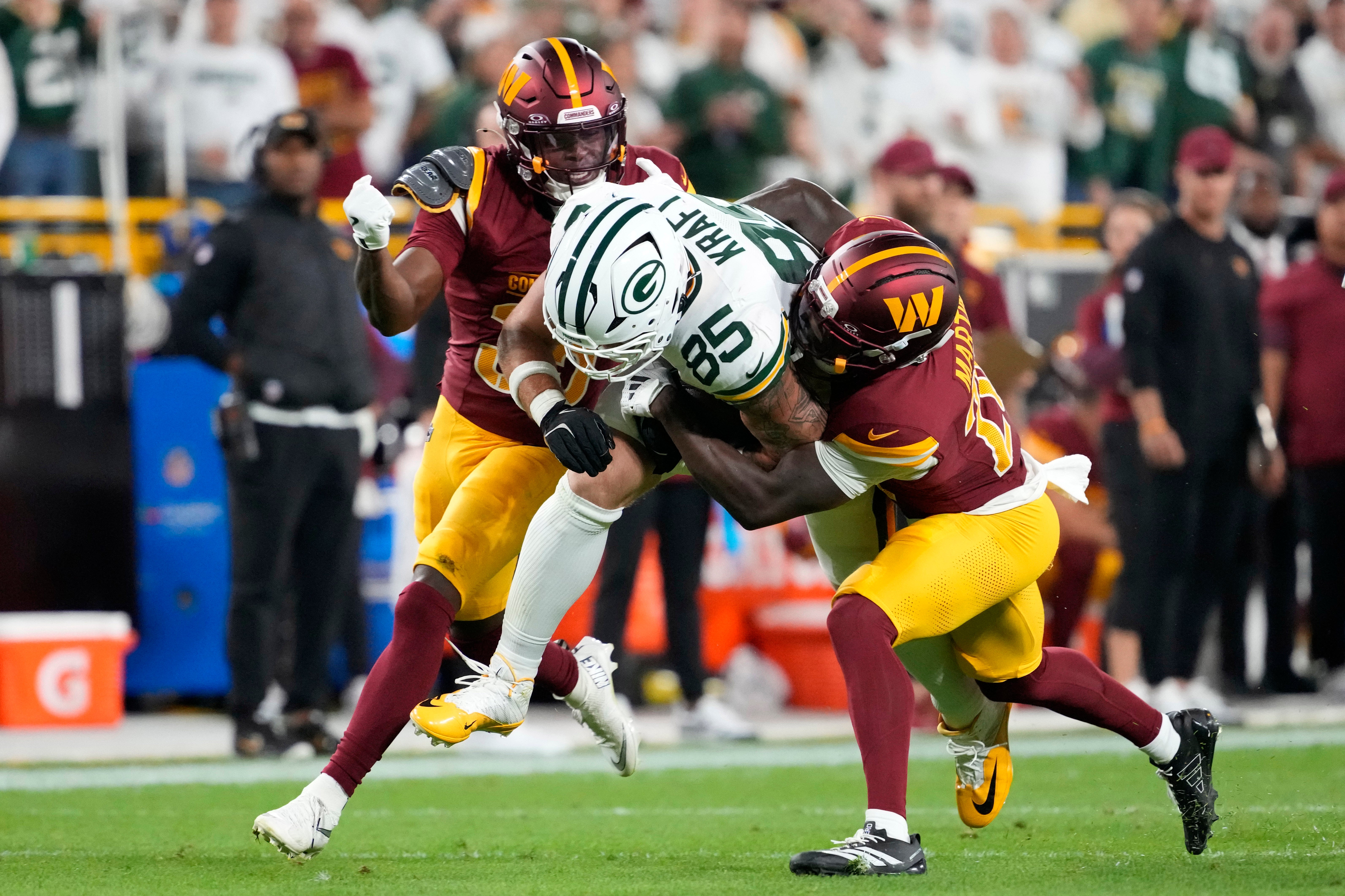 Sep 11, 2025; Green Bay, Wisconsin, USA; Washington Commanders safety Percy Butler (35) and safety Quan Martin (20) tackle Green Bay Packers tight end Tucker Kraft (85) in the first quarter at Lambeau Field.