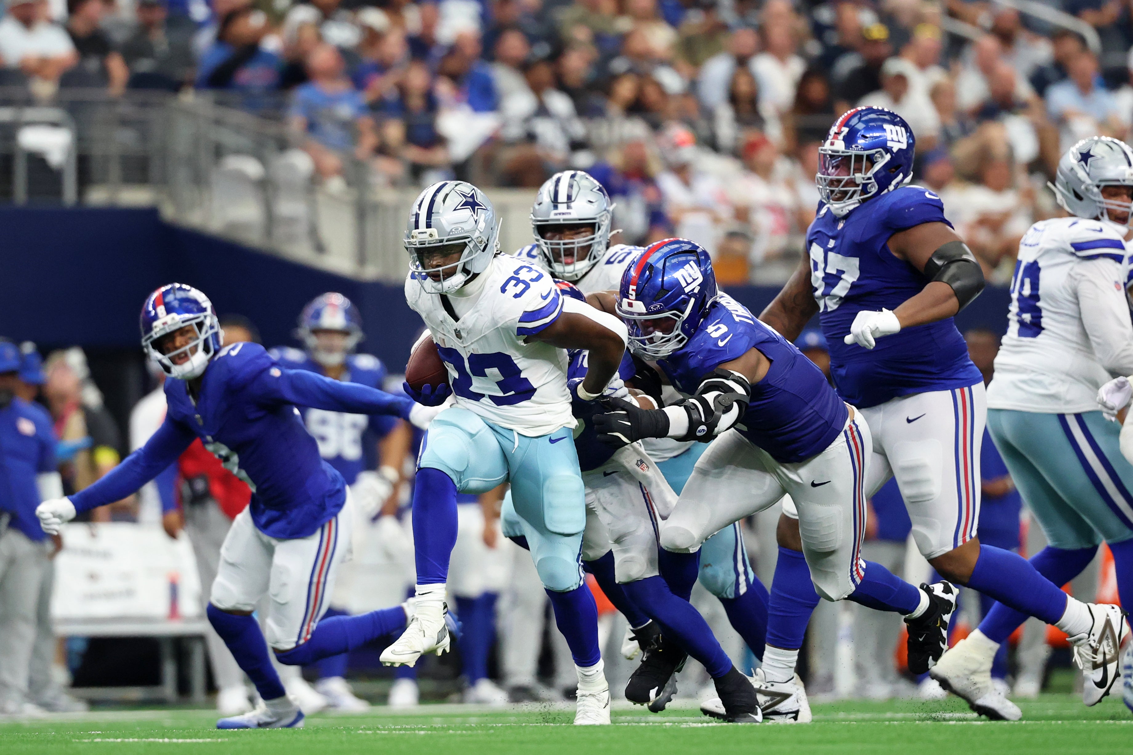 Sep 14, 2025; Arlington, Texas, USA; Dallas Cowboys running back Javonte Williams (33) runs with the ball against New York Giants linebacker Kayvon Thibodeaux (5) during the third quarter at AT&T Stadium.