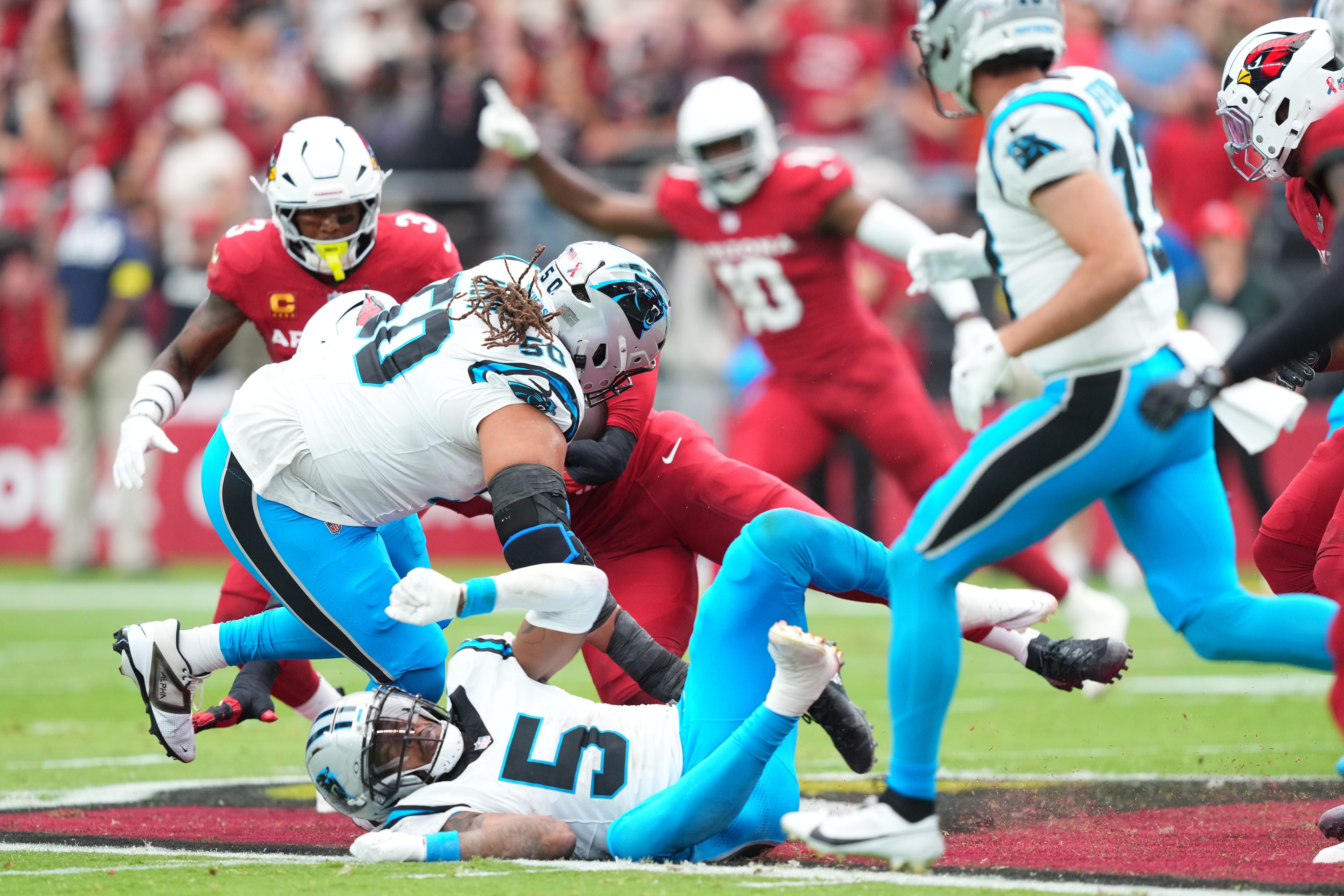 Sep 14, 2025; Glendale, Arizona, USA; Carolina Panthers guard Robert Hunt (50) and running back Rico Dowdle (5) defend against Arizona Cardinals during the first quarter at State Farm Stadium.