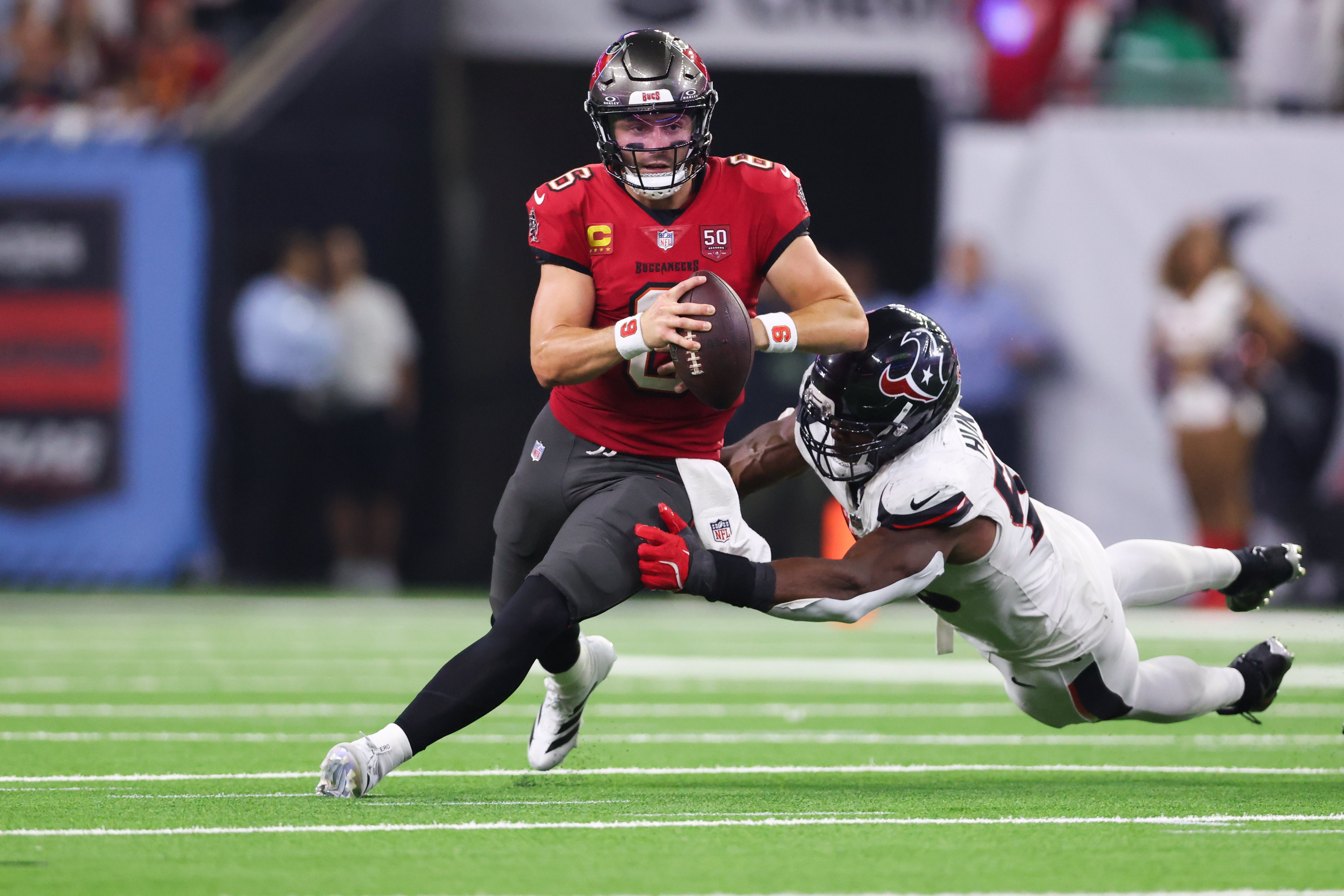Sep 15, 2025; Houston, Texas, USA; Tampa Bay Buccaneers quarterback Baker Mayfield (6) attempts to evade a tackle from Houston Texans defensive end Danielle Hunter (55) during the fourth quarter at NRG Stadium.