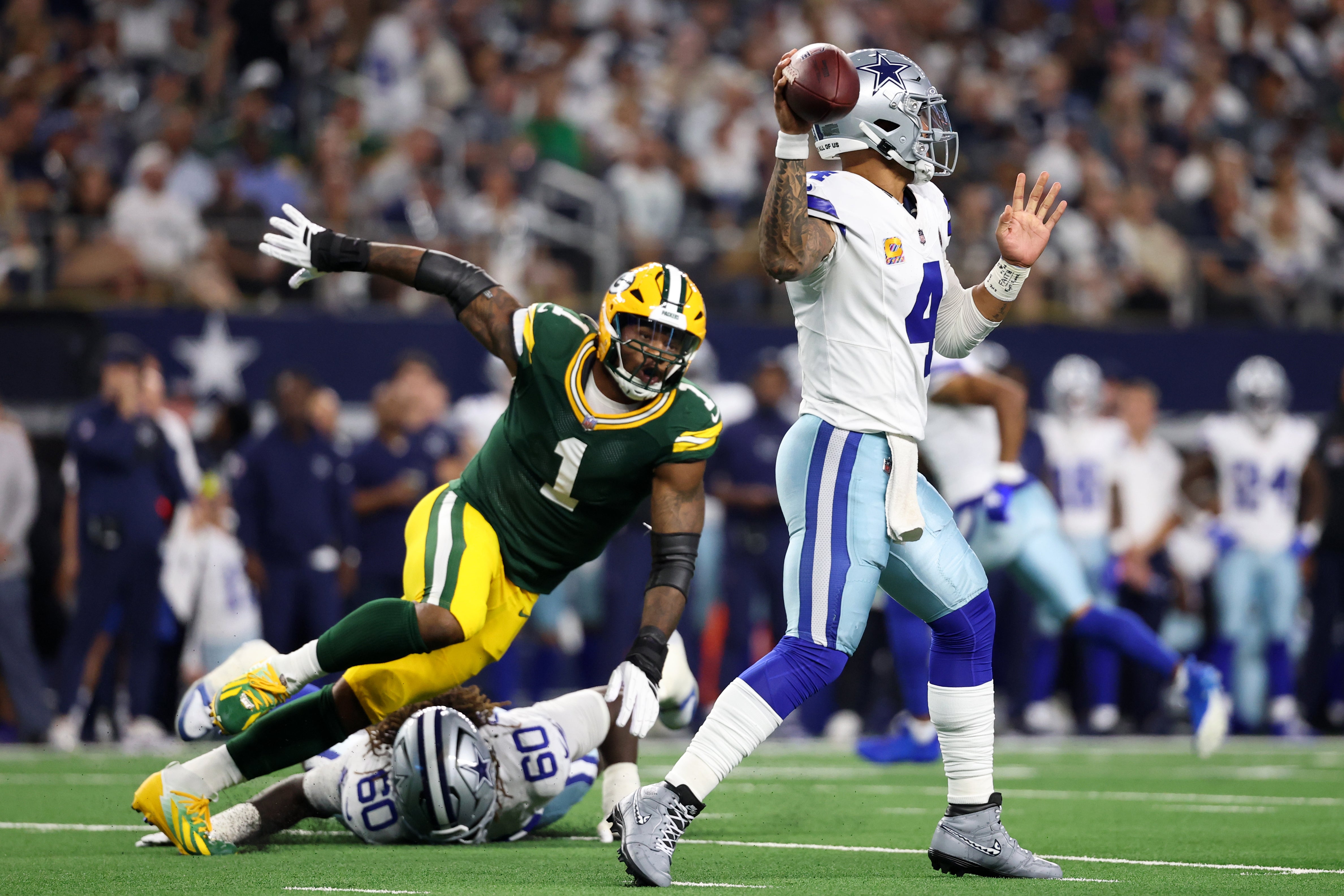 Sep 28, 2025; Arlington, Texas, USA; Dallas Cowboys quarterback Dak Prescott (4) throws under pressure from Green Bay Packers defensive end Micah Parsons (1) in the first quarter at AT&T Stadium.