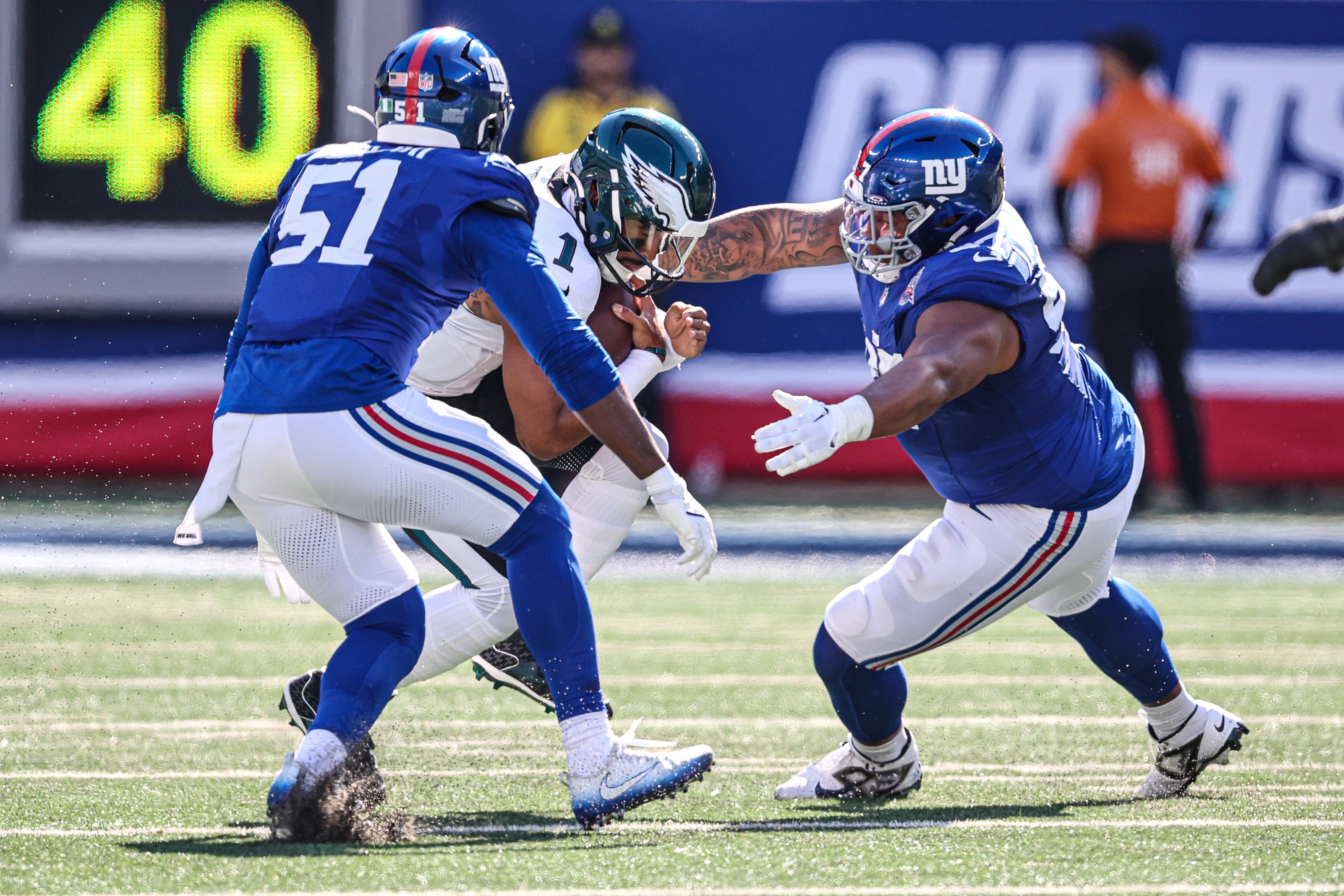 Oct 20, 2024; East Rutherford, New Jersey, USA; Philadelphia Eagles quarterback Jalen Hurts (1) is sacked by New York Giants defensive tackle Dexter Lawrence II (97) and linebacker Azeez Ojulari (51) during the first half at MetLife Stadium.