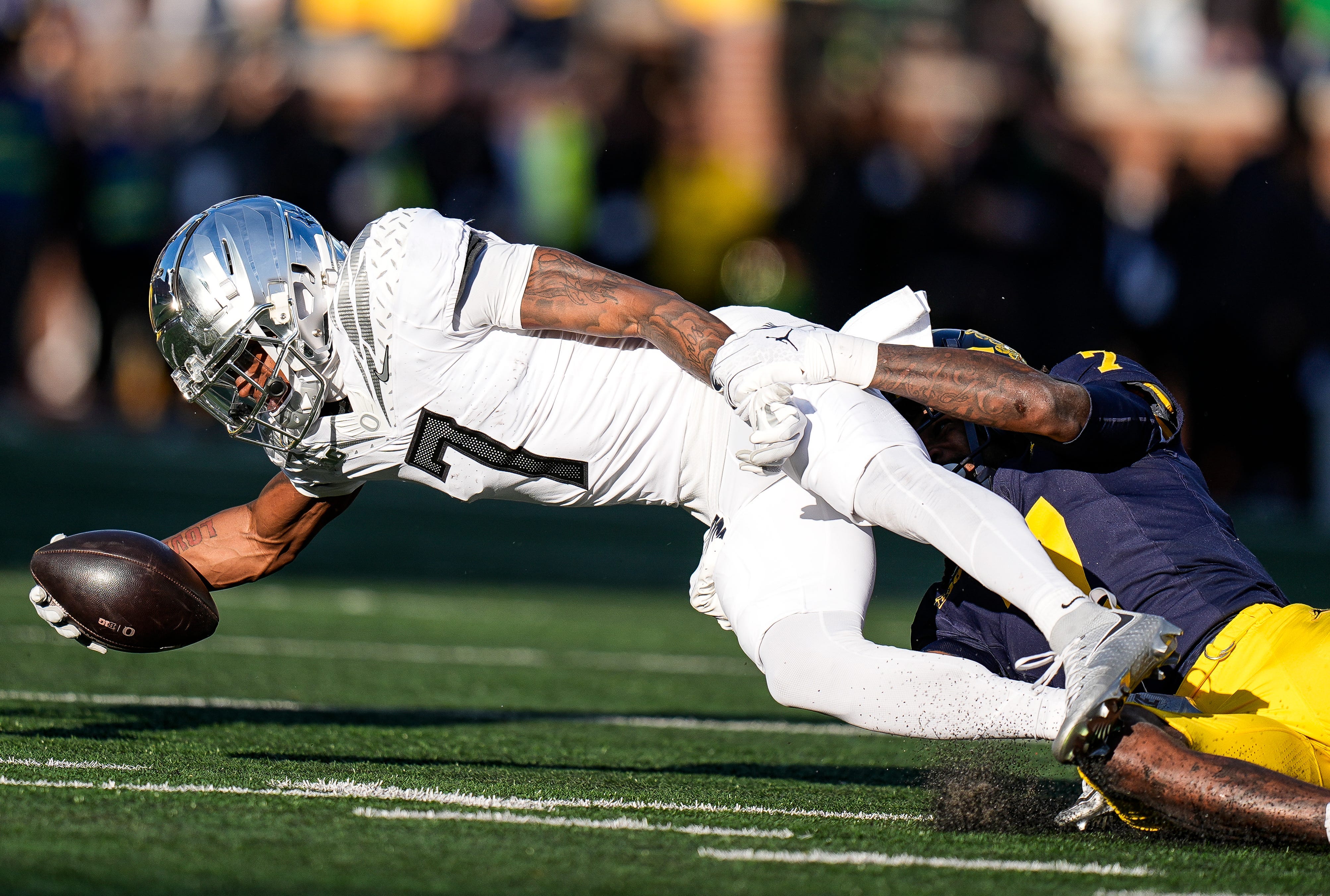 Oregon wide receiver Evan Stewart is tackled by Michigan defensive back Makari Paige during the first half at Michigan Stadium in Ann Arbor on Saturday, Nov. 2, 2024.