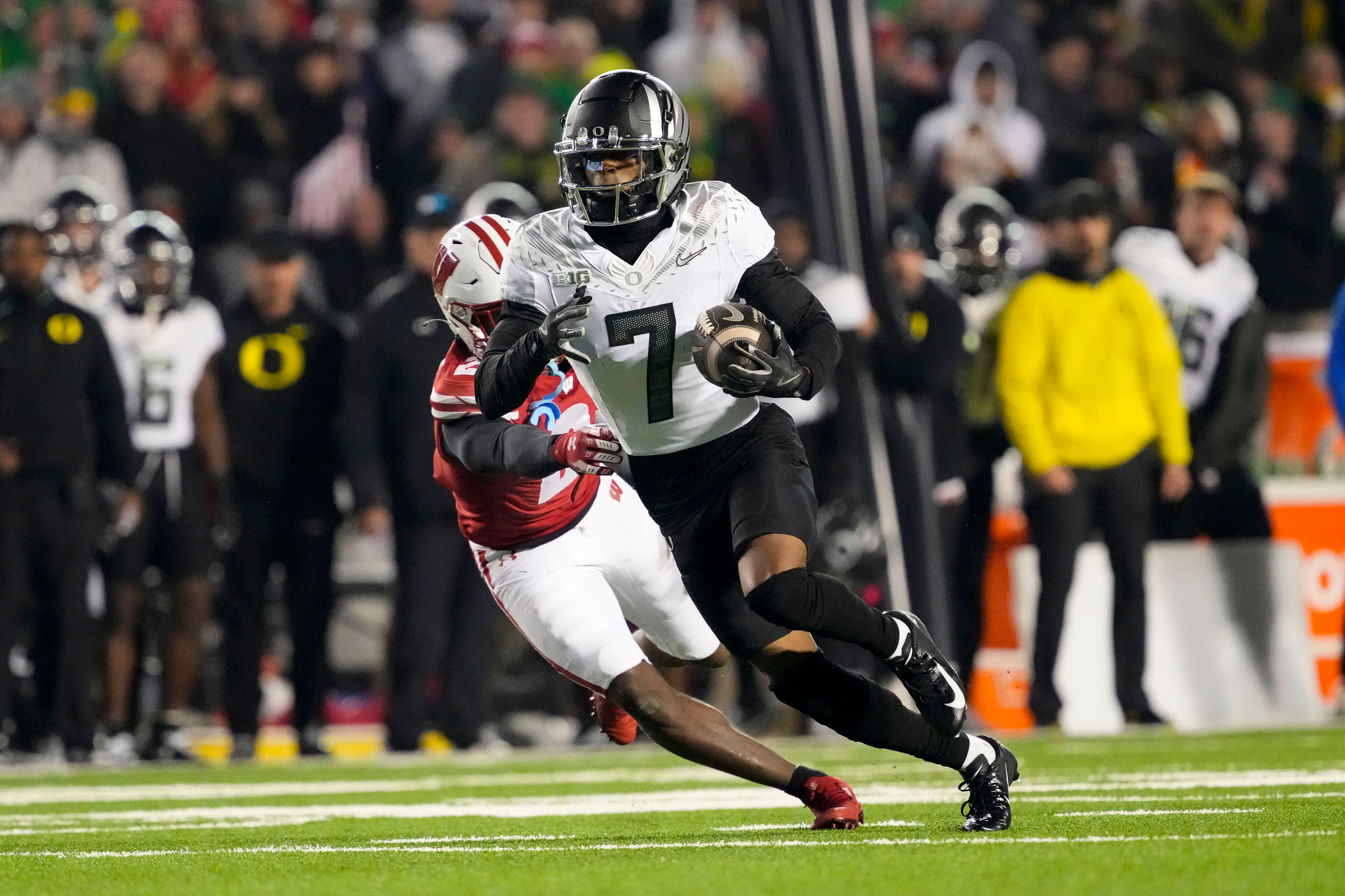 Nov 16, 2024; Madison, Wisconsin, USA; Oregon Ducks wide receiver Evan Stewart (7) rushes with the football in front of Wisconsin Badgers cornerback Ricardo Hallman (2) after catching a pass during the fourth quarter at Camp Randall Stadium. Mandatory Credit: Jeff Hanisch-Imagn Images