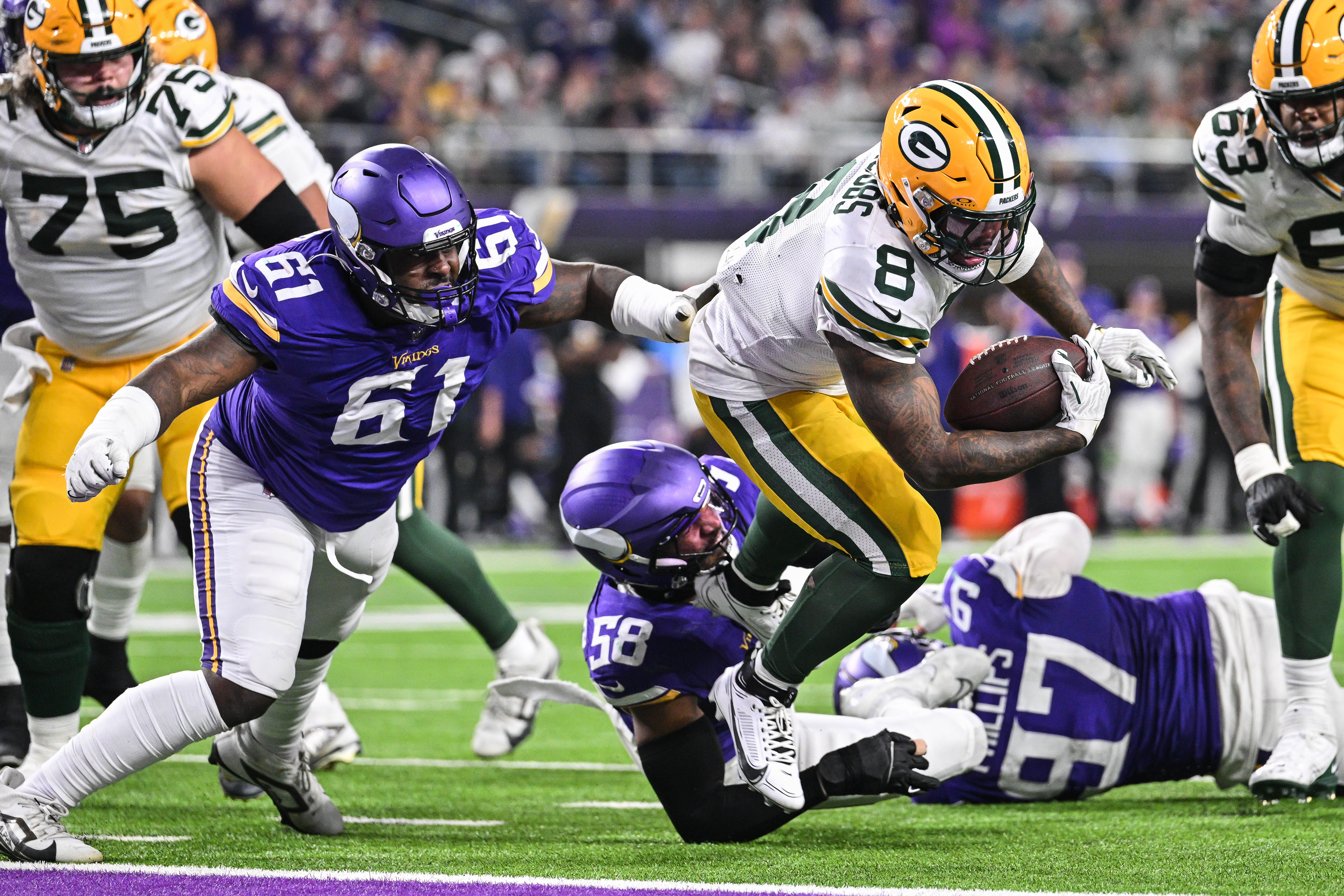 Dec 29, 2024; Minneapolis, Minnesota, USA; Green Bay Packers running back Josh Jacobs (8) runs for a touchdown as Minnesota Vikings defensive tackle Jalen Redmond (61) chases during the third quarter at U.S. Bank Stadium.