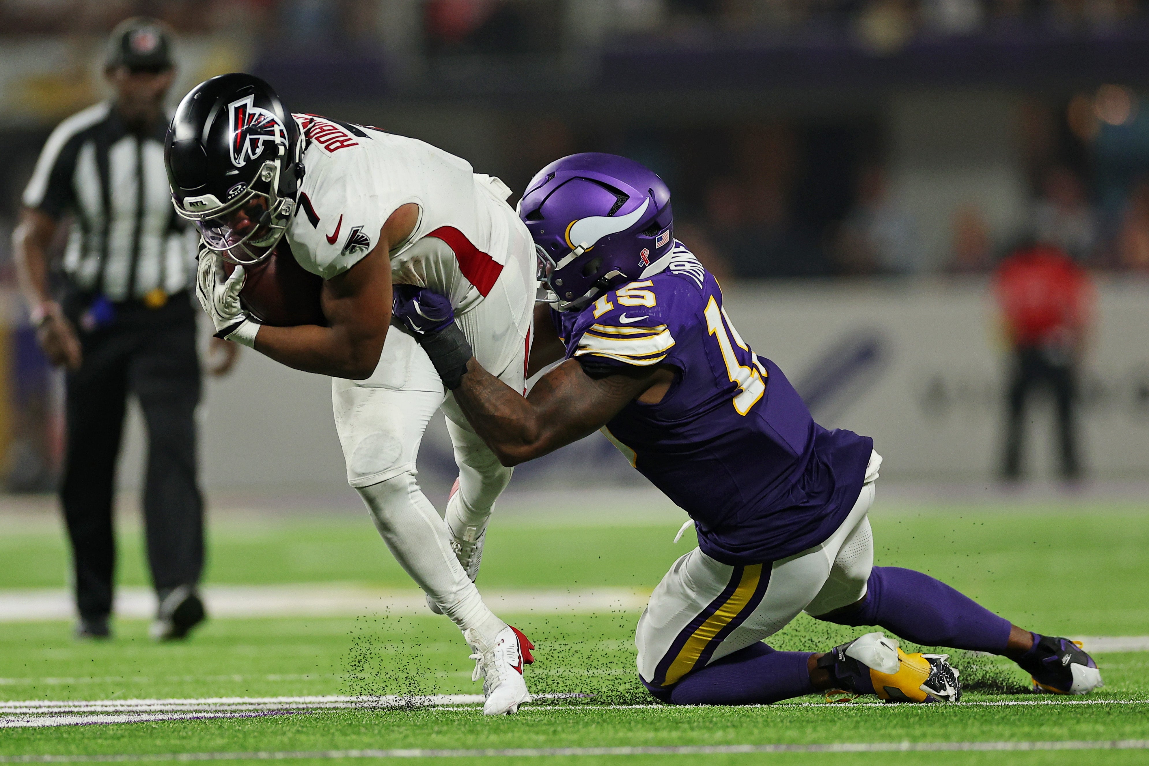 Sep 14, 2025; Minneapolis, Minnesota, USA; Atlanta Falcons running back Bijan Robinson (7) runs the ball and Minnesota Vikings edge rusher Dallas Turner (15) makes the tackle during the second half at U.S. Bank Stadium.