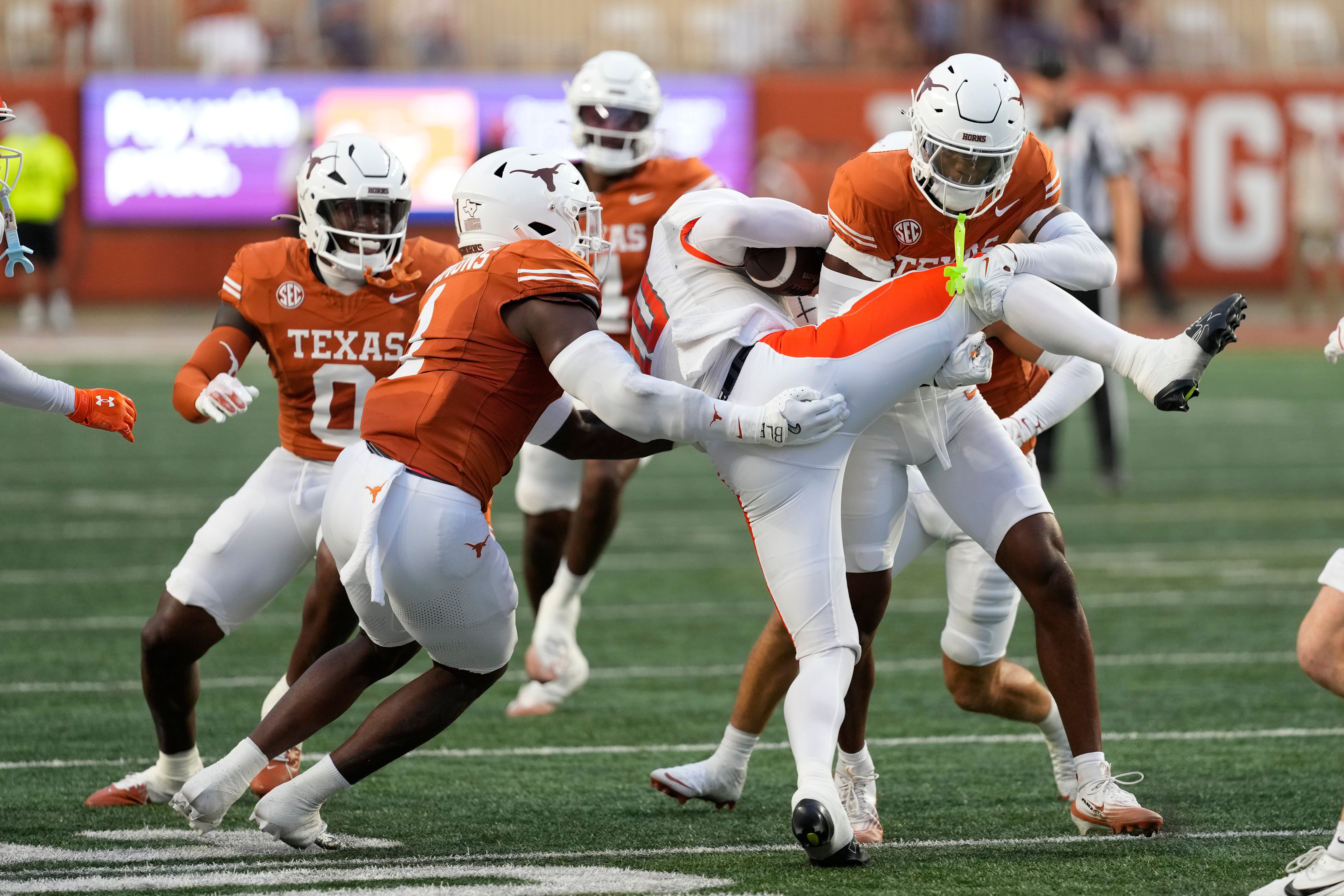 Sep 20, 2025; Austin, Texas, USA; Texas Longhorns defensive back Malik Muhammad (5) and defensive lineman Colin Simmons (1) tackle Sam Houston Bearkats quarterback Grant Gunnell (10) during the first half at Darrell K Royal-Texas Memorial Stadium.