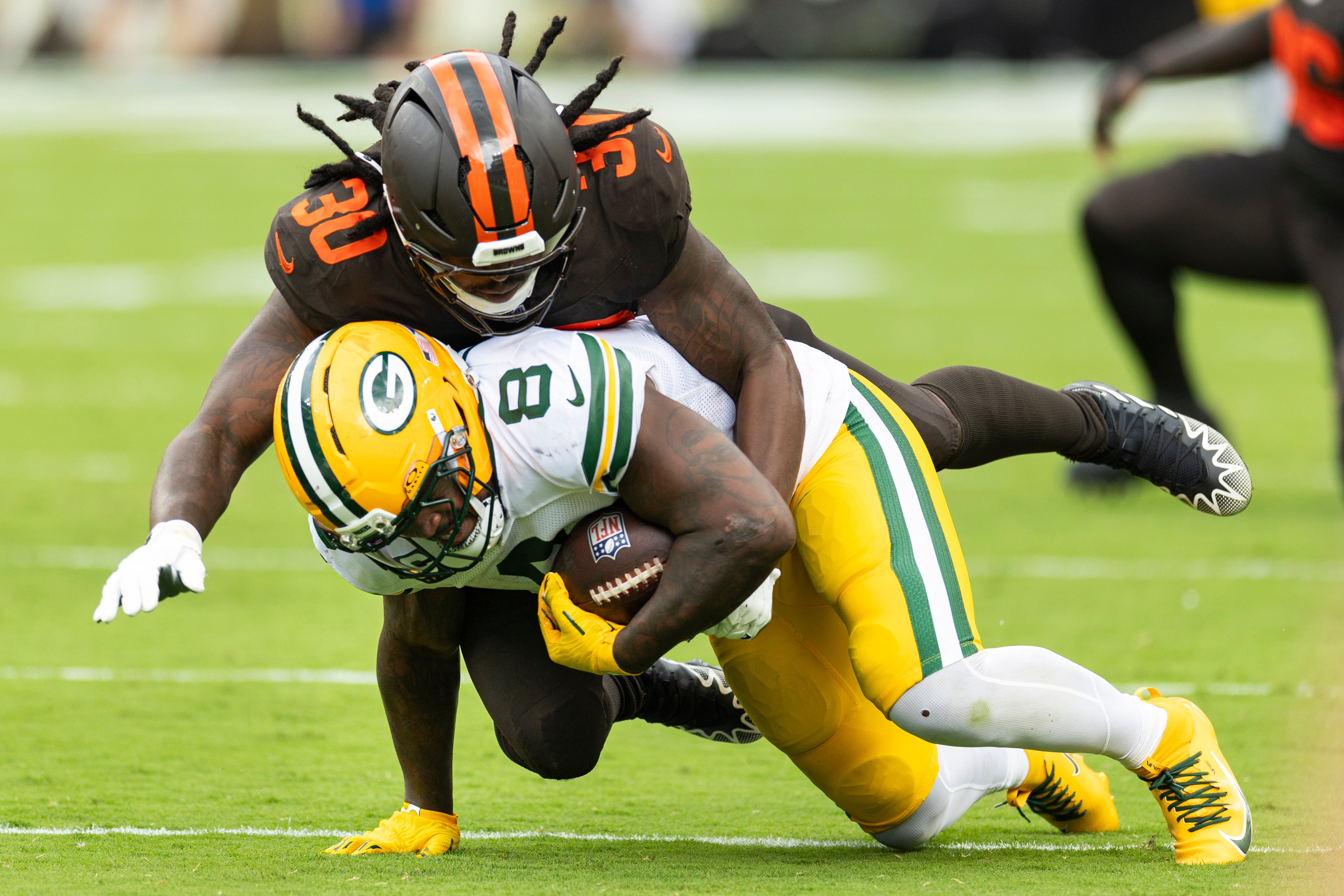 Sep 21, 2025; Cleveland, Ohio, USA; Cleveland Browns linebacker Devin Bush (30) tackles Green Bay Packers running back Josh Jacobs (8) during the third quarter at Huntington Bank Field.