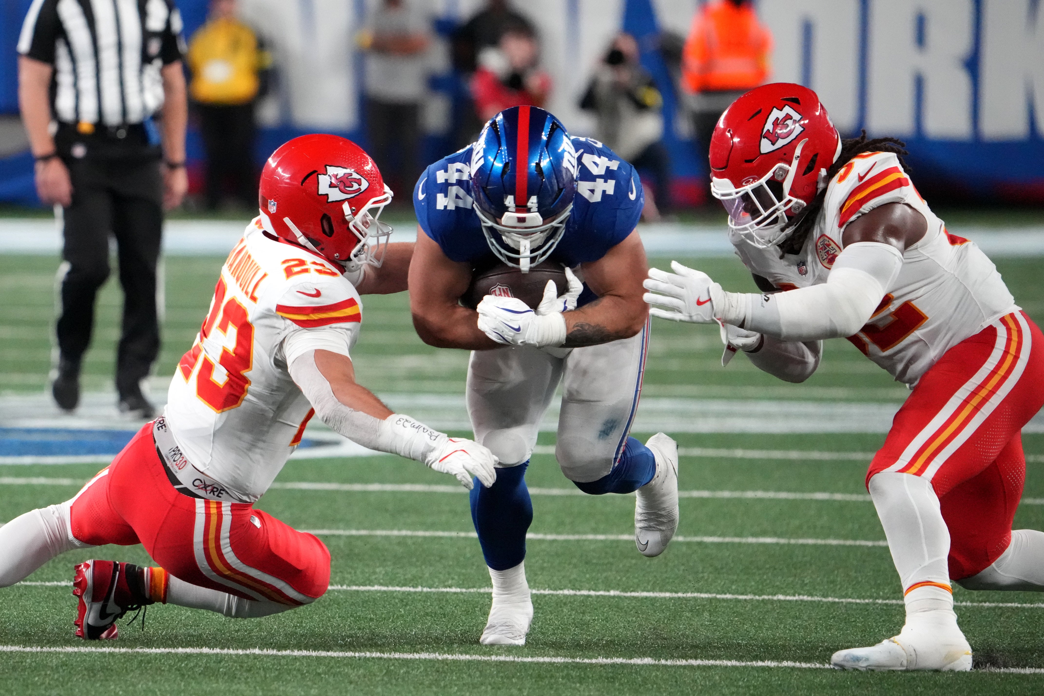 New York Giants running back Cam Skattebo (44) runs against Kansas City Chiefs linebacker Drue Tranquill (23) and linebacker Nick Bolton (32)
