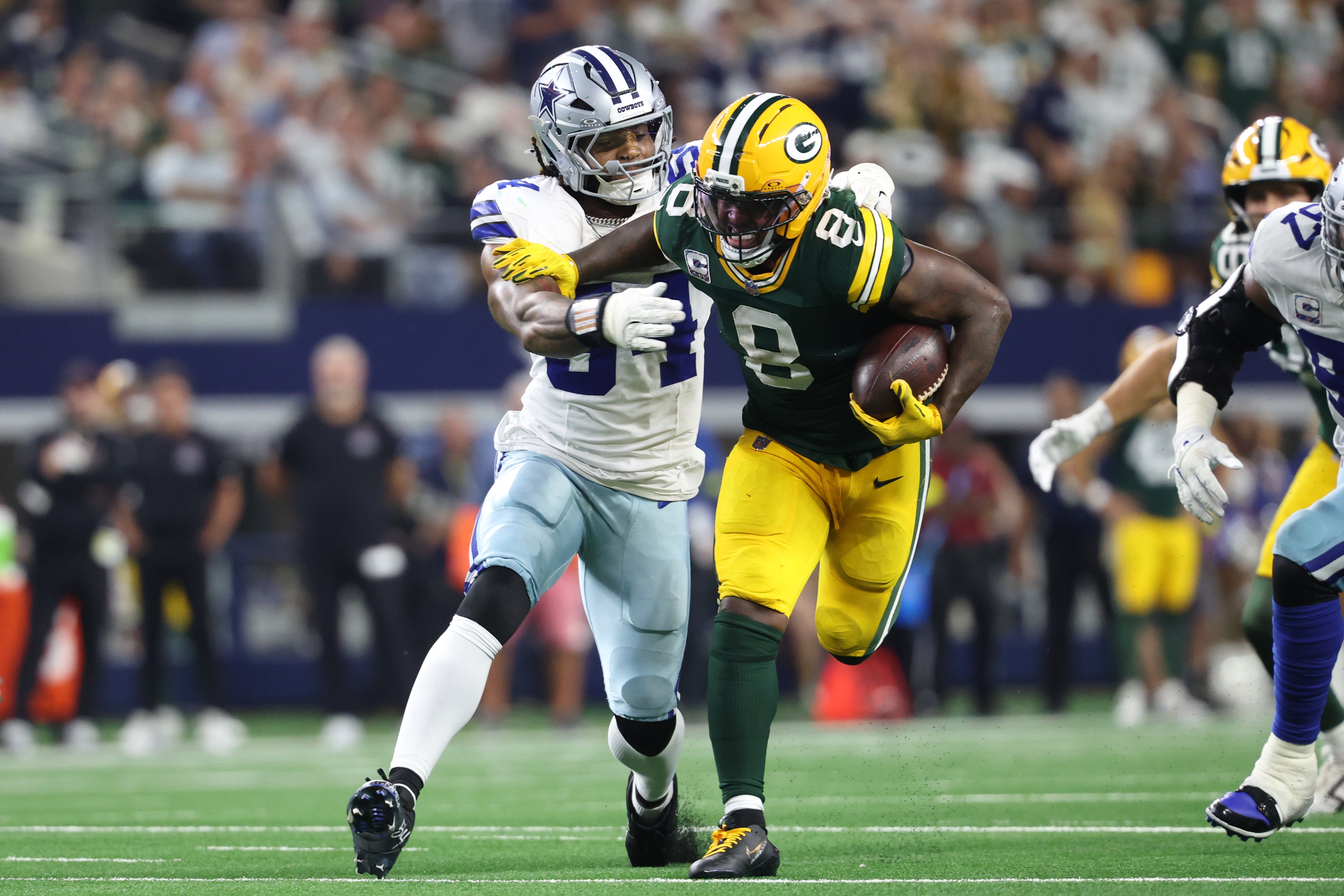 Sep 28, 2025; Arlington, Texas, USA; Green Bay Packers running back Josh Jacobs (8) runs against Dallas Cowboys defensive end Sam Williams (54) in the fourth quarter at AT&T Stadium.