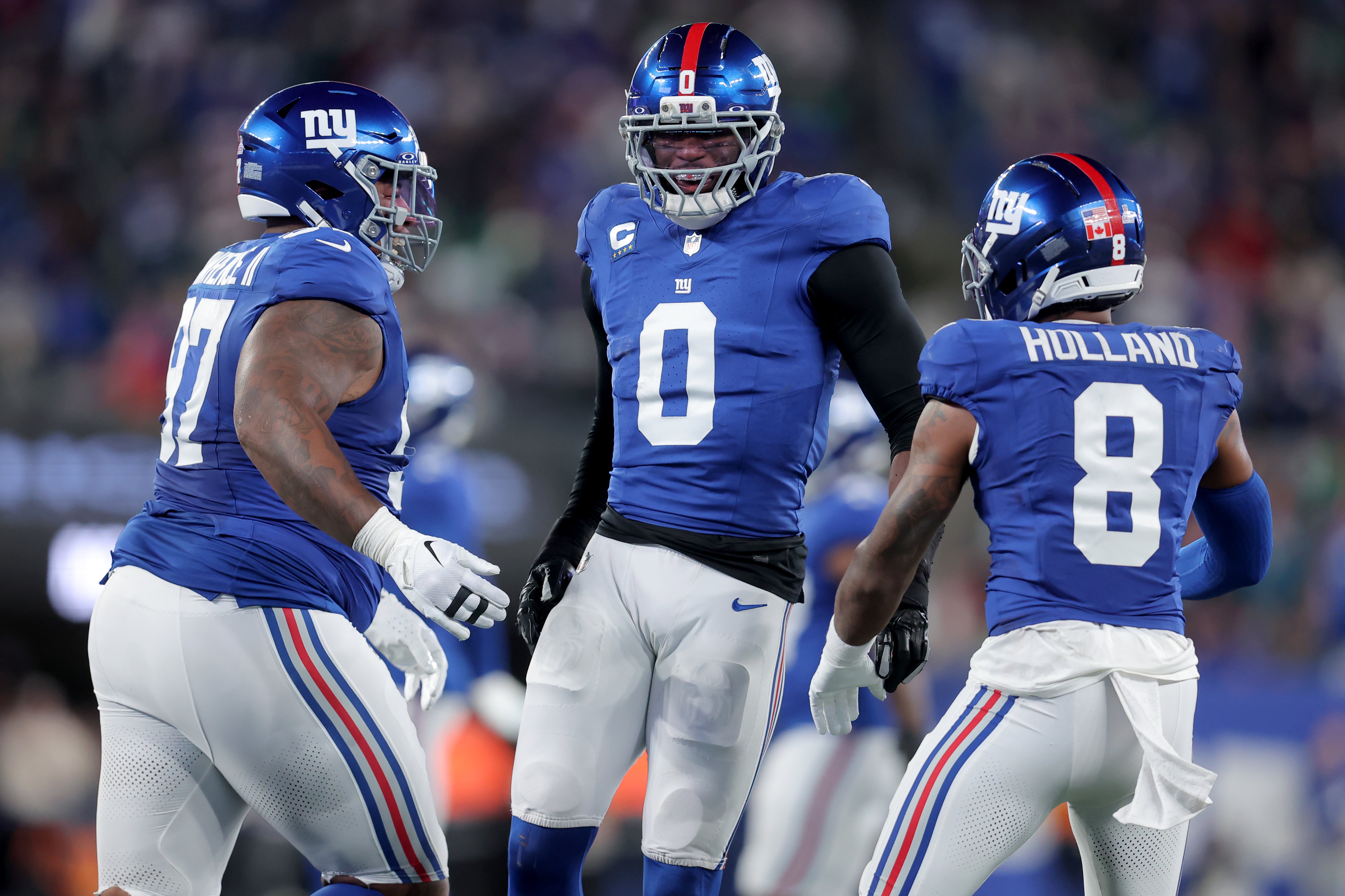 Oct 9, 2025; East Rutherford, New Jersey, USA; New York Giants linebacker Brian Burns (0) celebrates his sack of Philadelphia Eagles quarterback Jalen Hurts (not pictured) with defensive tackle Dexter Lawrence (97) and safety Jevon Holland (8) during the first quarter at MetLife Stadium.