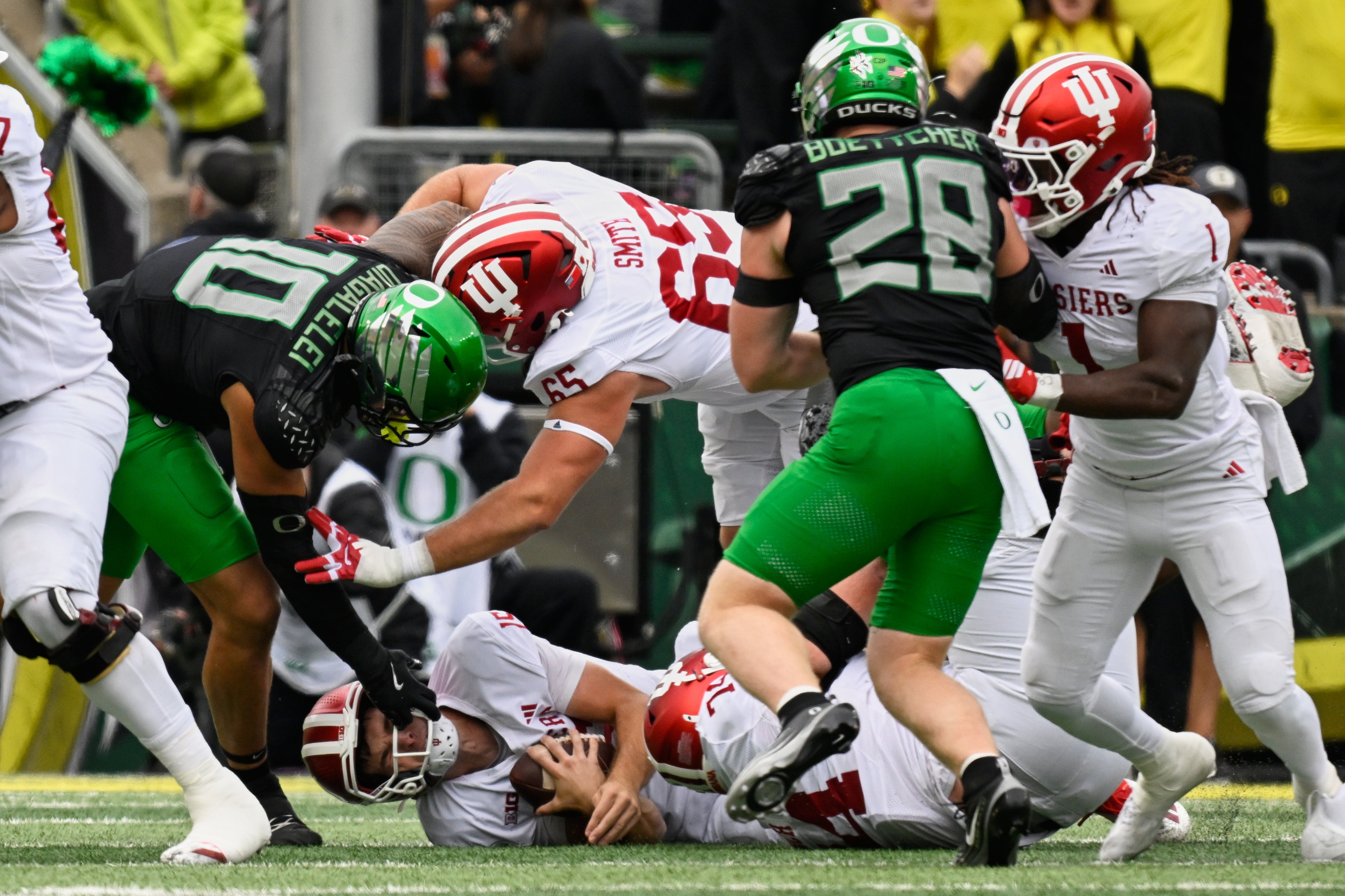 Oct 11, 2025; Eugene, Oregon, USA; Indiana Hoosiers quarterback Fernando Mendoza (15) takes a sack near offensive lineman Carter Smith (65) against Oregon Ducks linebacker Matayo Uiagalelei (10) and linebacker Bryce Boettcher (28) during the first quarter at Autzen Stadium. Mandatory Credit: Troy Wayrynen-Imagn Images