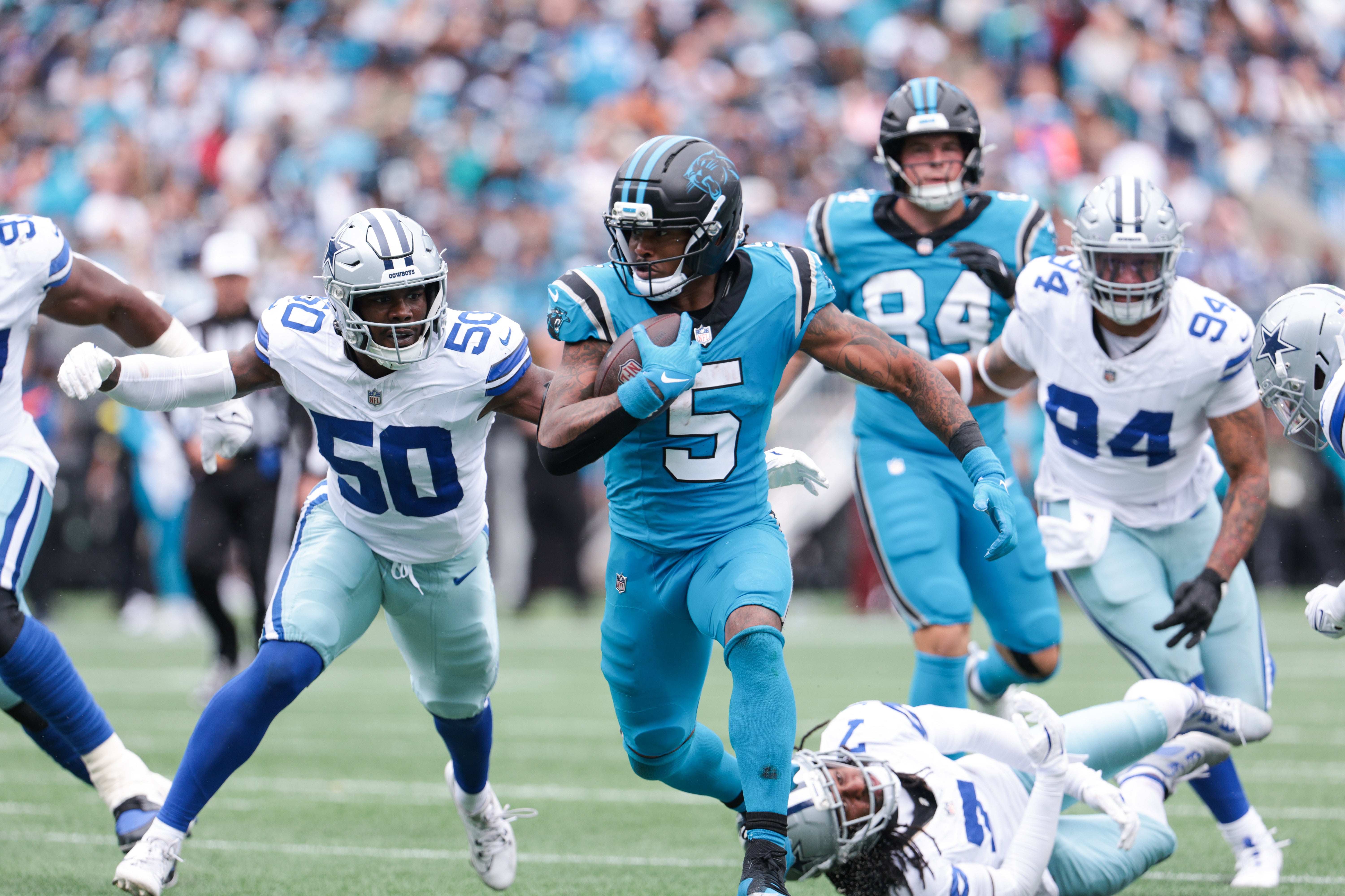 Oct 12, 2025; Charlotte, North Carolina, USA; Carolina Panthers running back Rico Dowdle (5) runs with the ball while getting pressured by Dallas Cowboys linebacker Shemar James (50) during the second half at Bank of America Stadium.