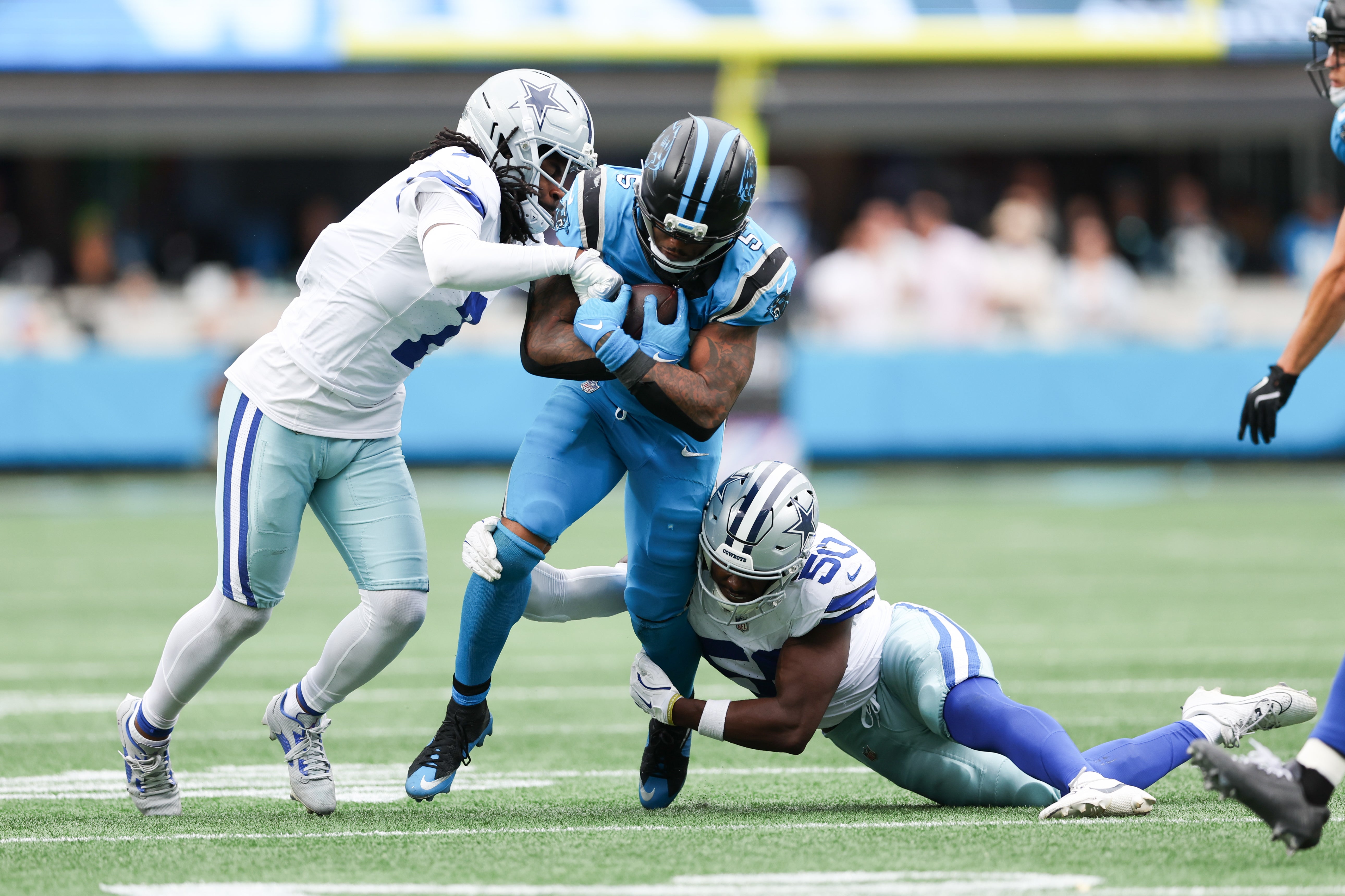 Oct 12, 2025; Charlotte, North Carolina, USA; Carolina Panthers running back Rico Dowdle (5) runs with the ball while being tackled by Dallas Cowboys linebacker Shemar James (50) during the second half at Bank of America Stadium.