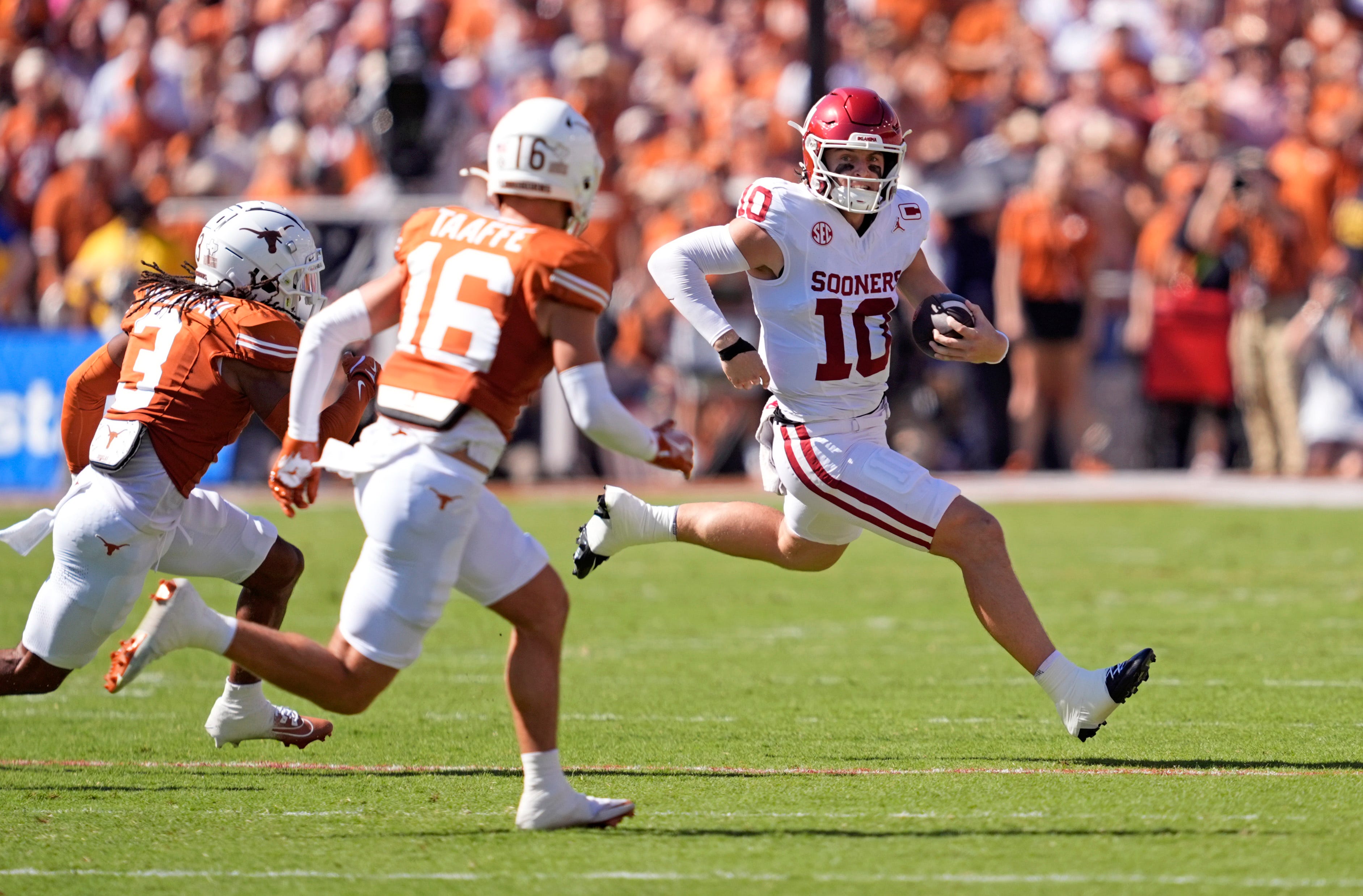Oklahoma Sooners quarterback John Mateer (10) rushes as Texas Longhorns defensive back Jaylon Guilbeau (3) and Texas Longhorns defensive back Michael Taaffe (16) defend in the first half of the Red River Rivalry college football game between the University of Oklahoma Sooners and the Texas Longhorn at the Cotton Bowl Stadium in Dallas, Texas, Saturday, Oct. 11, 2025.