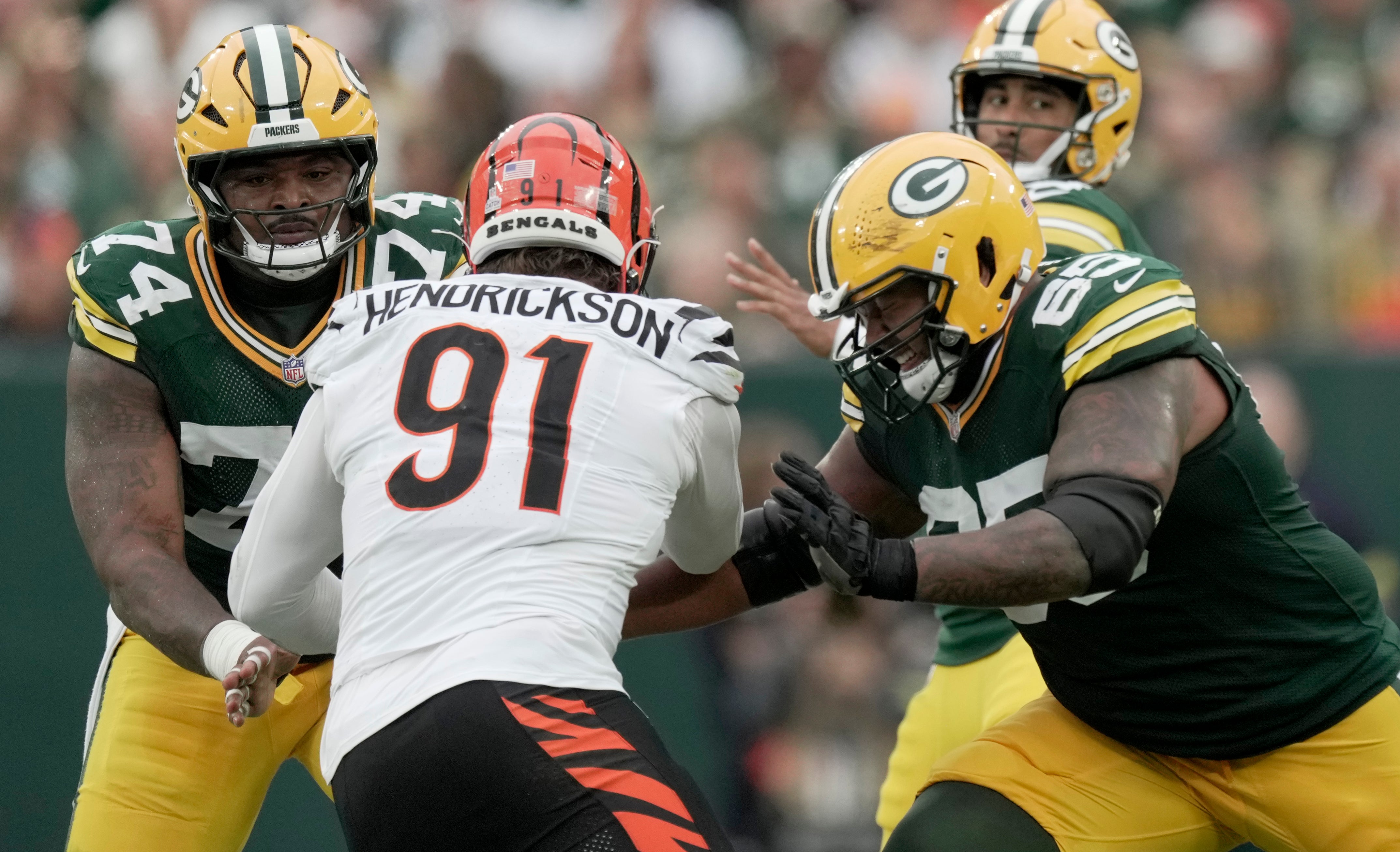 Oct 12, 2025; Green Bay, Wisconsin, USA; Cincinnati Bengals defensive end Trey Hendrickson (91) is double-teamed by Green Bay Packers center Elgton Jenkins (74) and guard Aaron Banks (65) during the second quarter of their game at Lambeau Field.