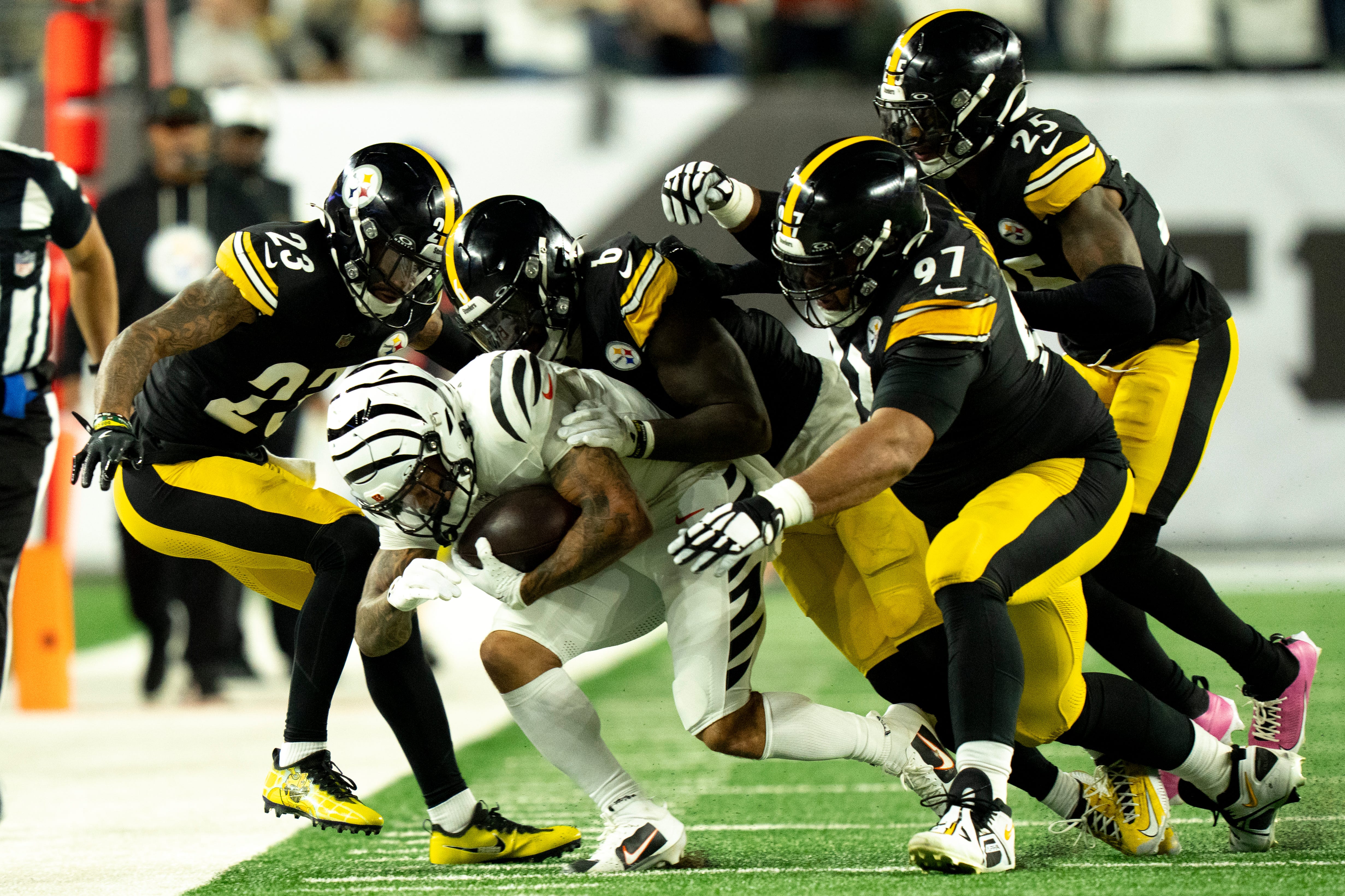 Cincinnati Bengals running back Chase Brown (30) is tackled by a group of Pittsburgh Steelers defenders in the second quarter of the NFL game between the Cincinnati Bengals and Pittsburgh Steelers at Paycor Stadium in Cincinnati on Oct. 16, 2025.