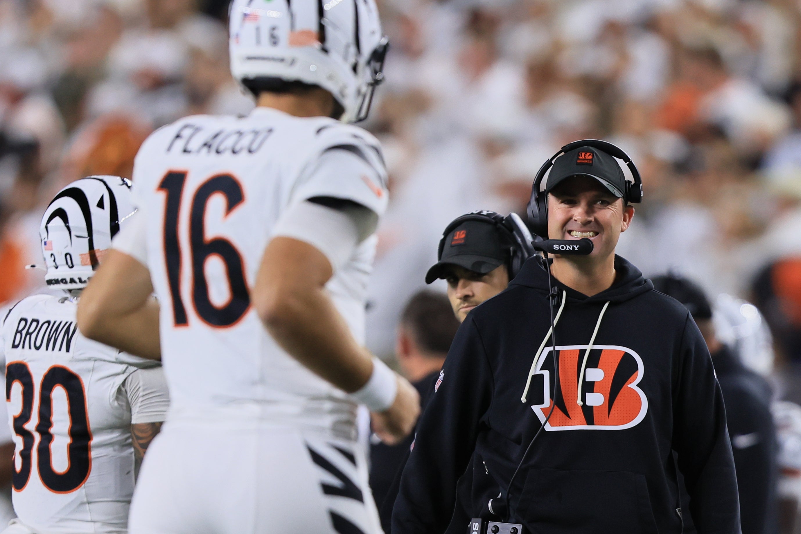 Oct 16, 2025; Cincinnati, Ohio, USA; Cincinnati Bengals head coach Zac Taylor smiles at quarterback Joe Flacco (16) (obscured) as Flacco runs to the sideline during the fourth quarter against the Pittsburgh Steelers at Paycor Stadium.