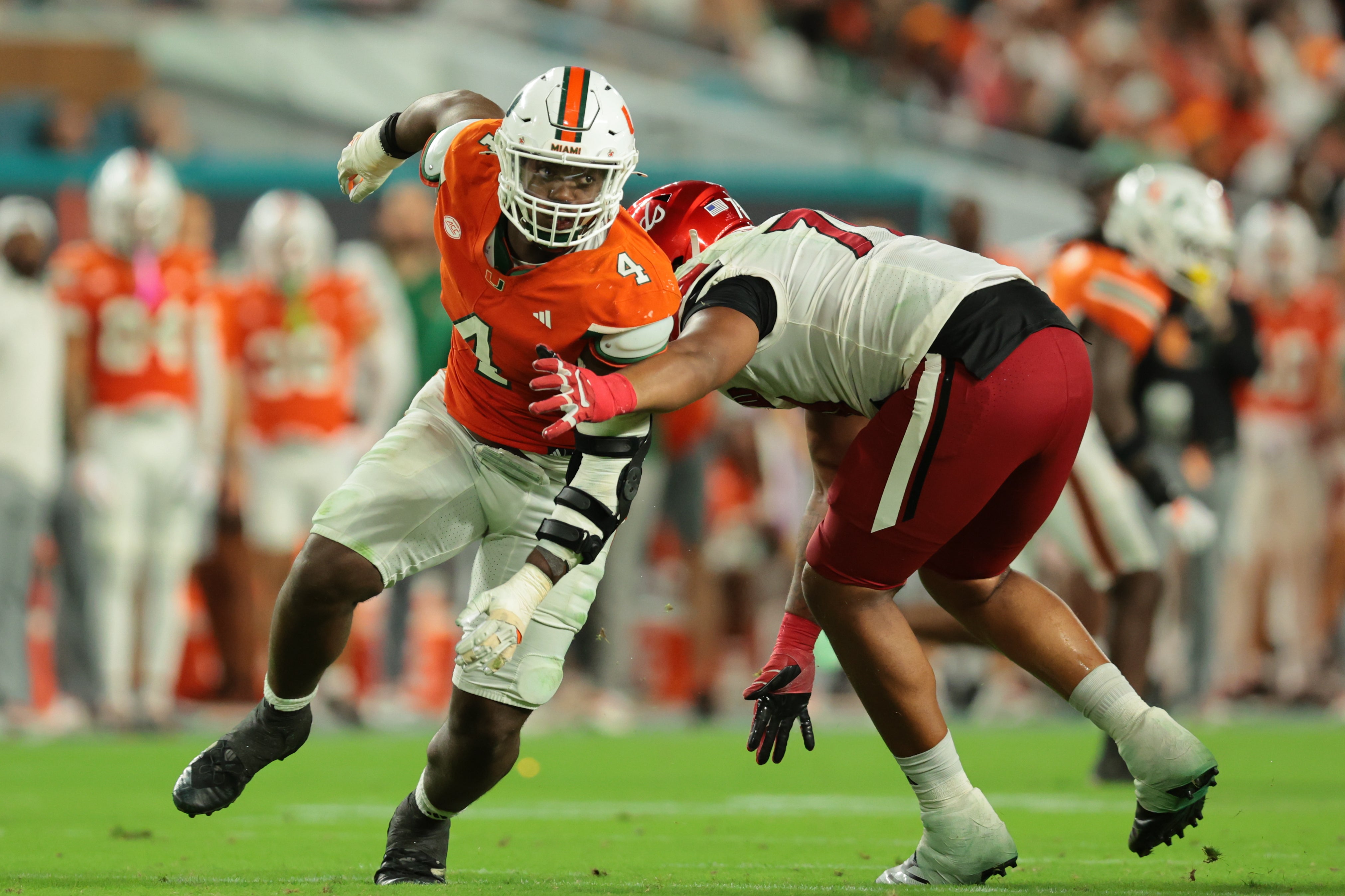 Oct 17, 2025; Miami Gardens, Florida, USA; Miami Hurricanes defensive lineman Rueben Bain Jr. (4) escapes coverage against Louisville Cardinals offensive lineman Trevonte Sylvester (70) during the third quarter at Hard Rock Stadium. Mandatory Credit: Sam Navarro-Imagn Images