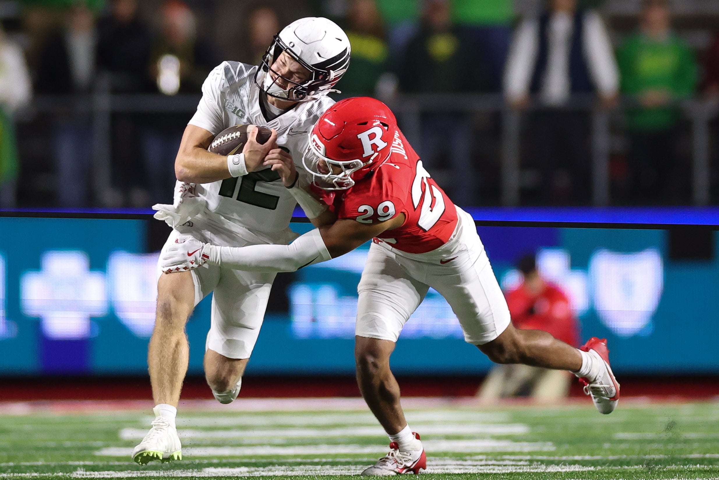 Oct 18, 2025; Piscataway, New Jersey, USA; Oregon Ducks quarterback Brock Thomas (12) is tackled by Rutgers Scarlet Knights defensive back Sebastian Jusma (29) during the second half at SHI Stadium. Mandatory Credit: Vincent Carchietta-Imagn Images
