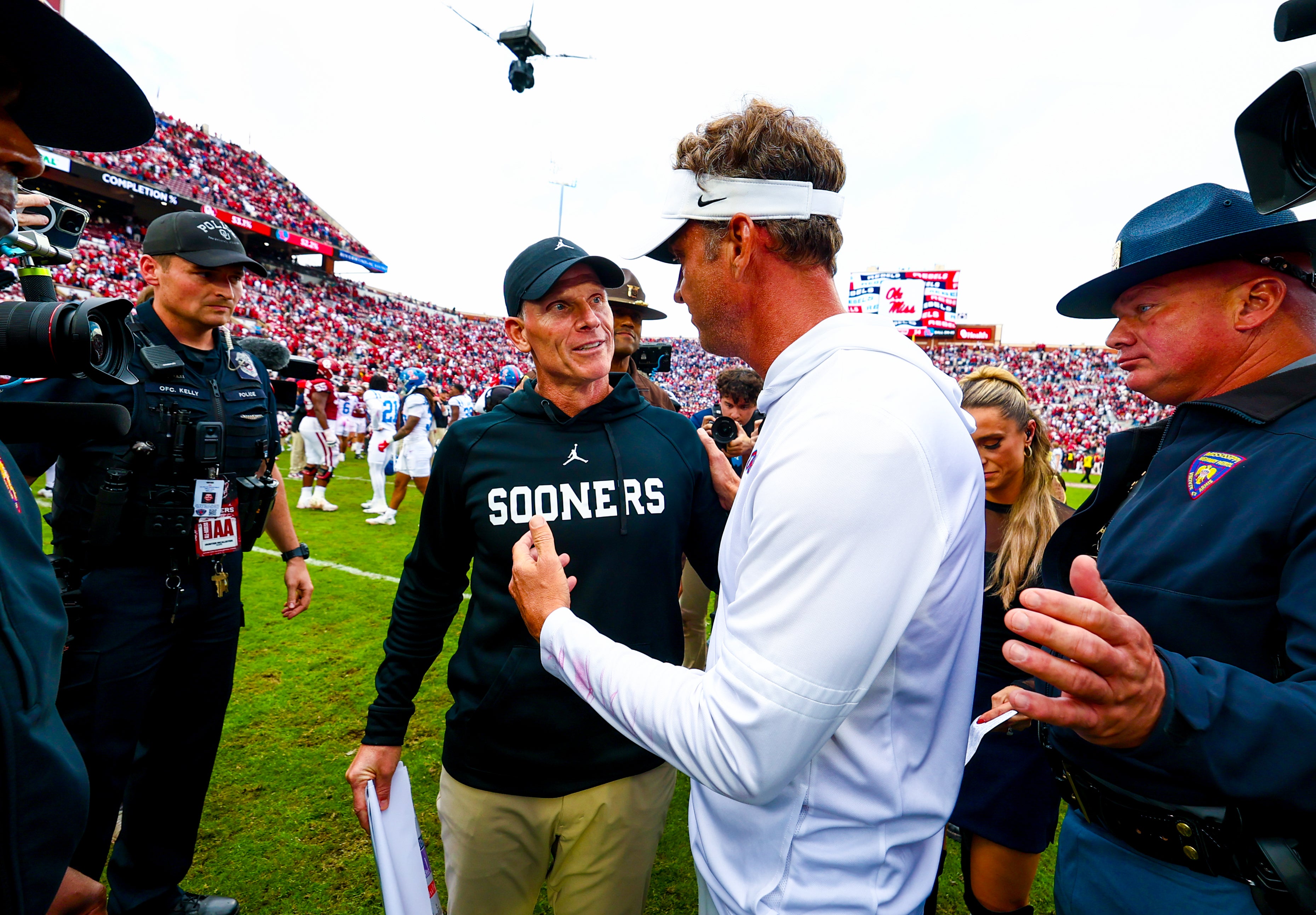 Oct 25, 2025; Norman, Oklahoma, USA; Ole Miss Rebels head coach Lane Kiffin (right) greets Oklahoma Sooners head coach Brent Venables (left) after the game at Gaylord Family-Oklahoma Memorial Stadium.