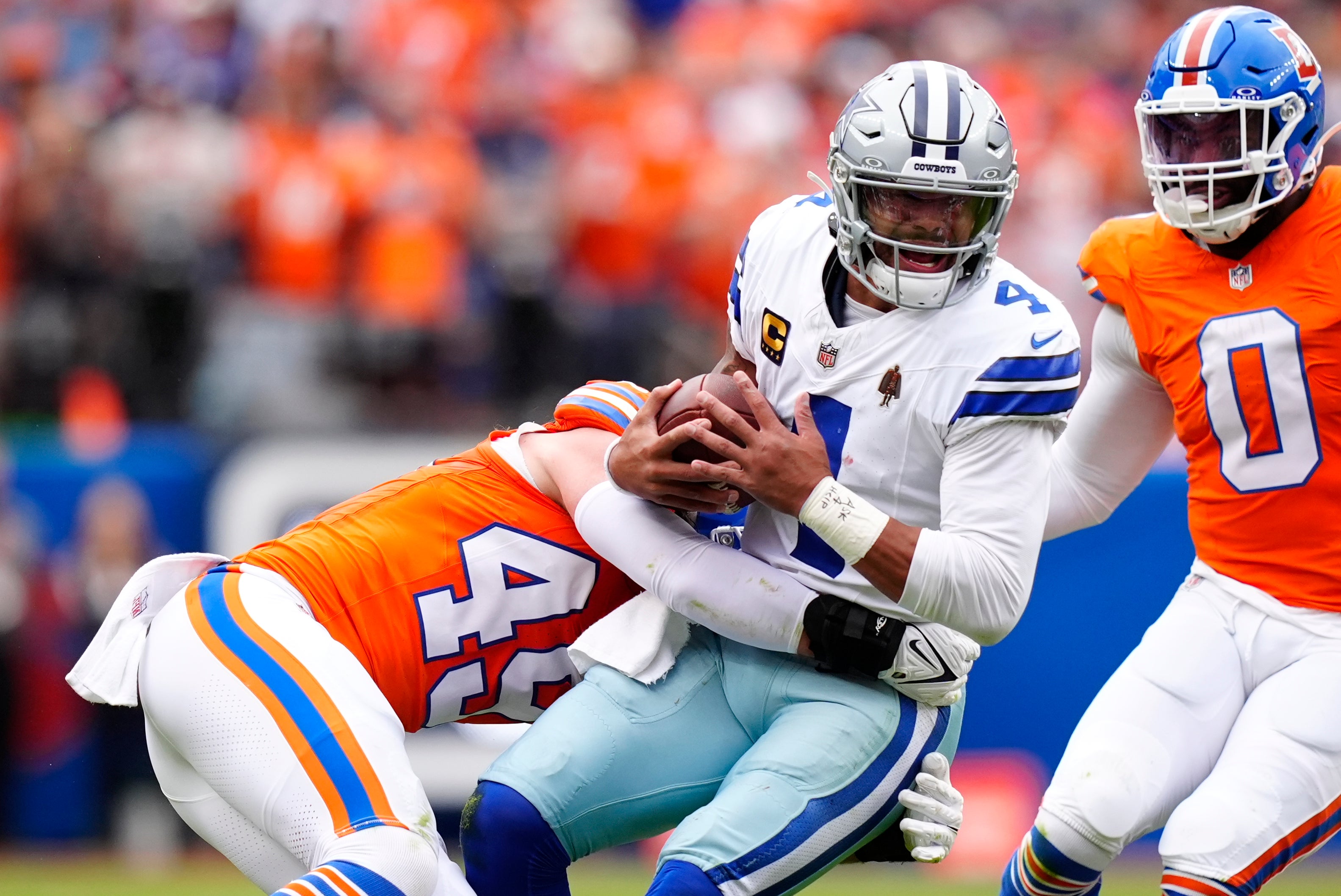 Oct 26, 2025; Denver, Colorado, USA; Denver Broncos linebacker Alex Singleton (49) tackles Dallas Cowboys quarterback Dak Prescott (4) in the first half at Empower Field at Mile High.